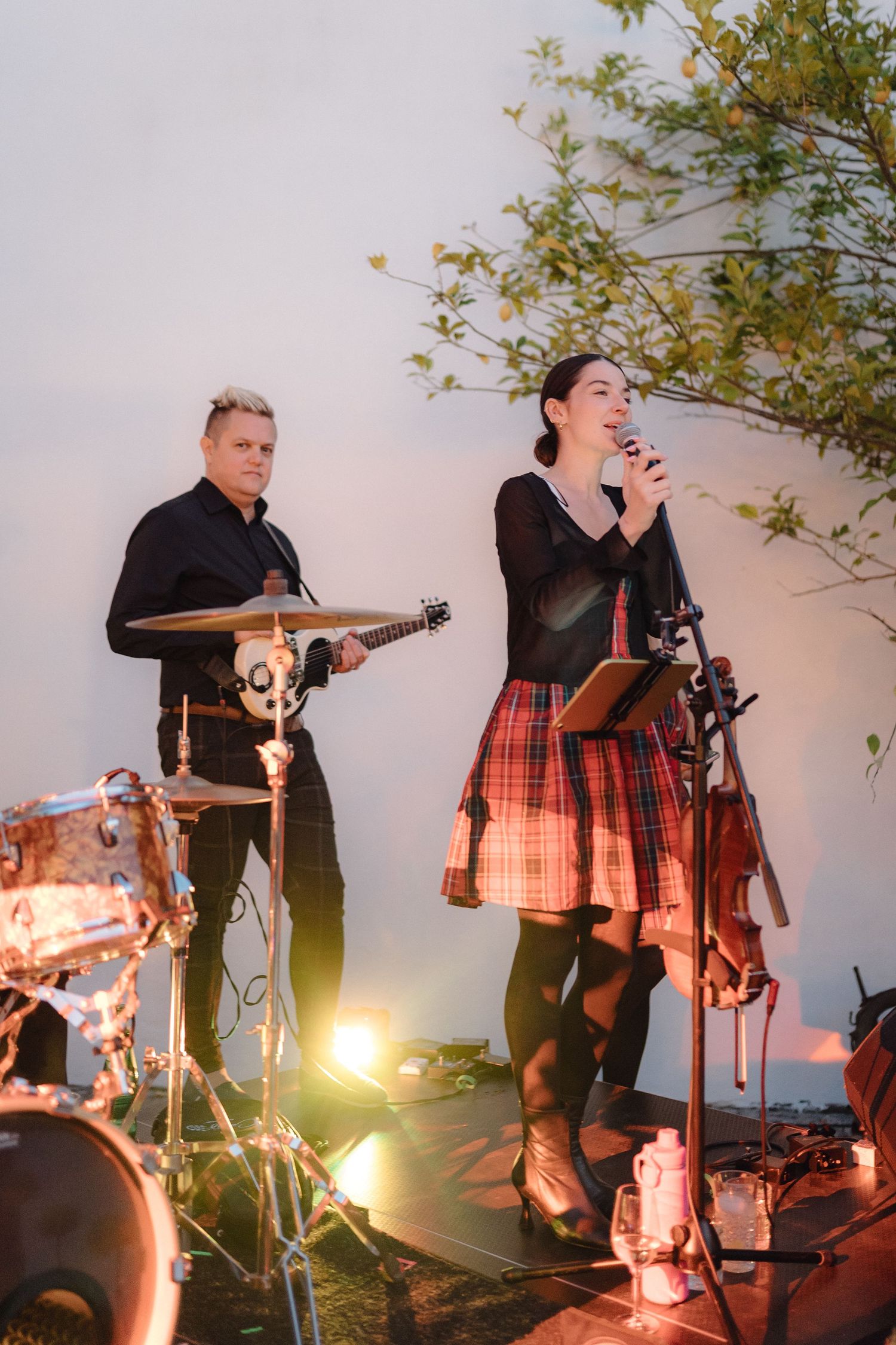 Musicians performing with instruments at sunset during an outdoor event.