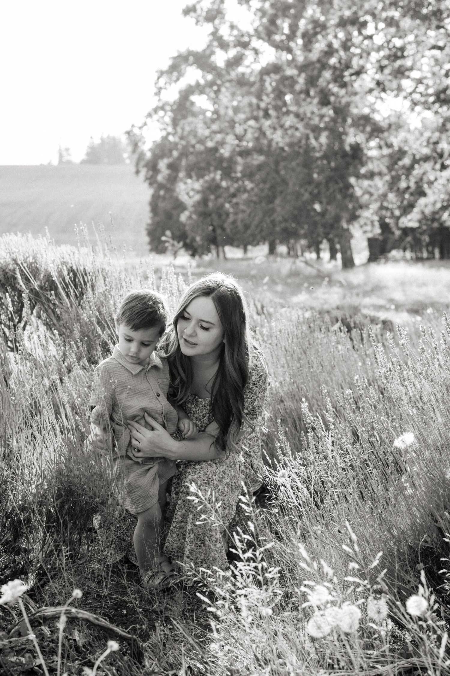 A tender black and white moment captured in a meadow of tall grass on a sunny afternoon.