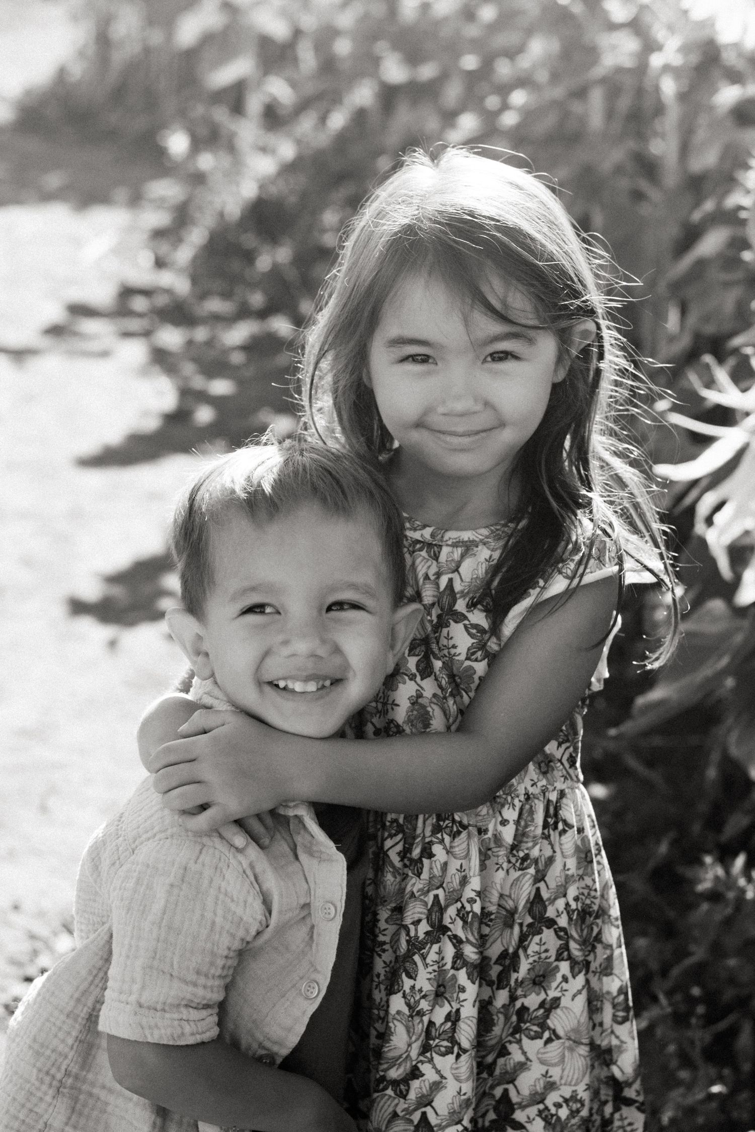 A series of black and white photographs showing two siblings hugging and playing together outdoors.
