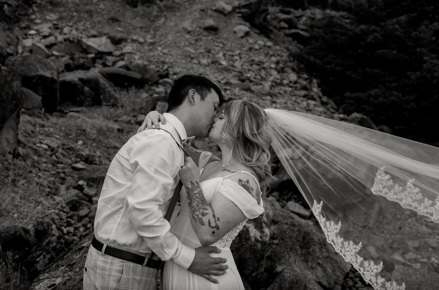 A black and white romantic moment captured with a flowing veil in nature.