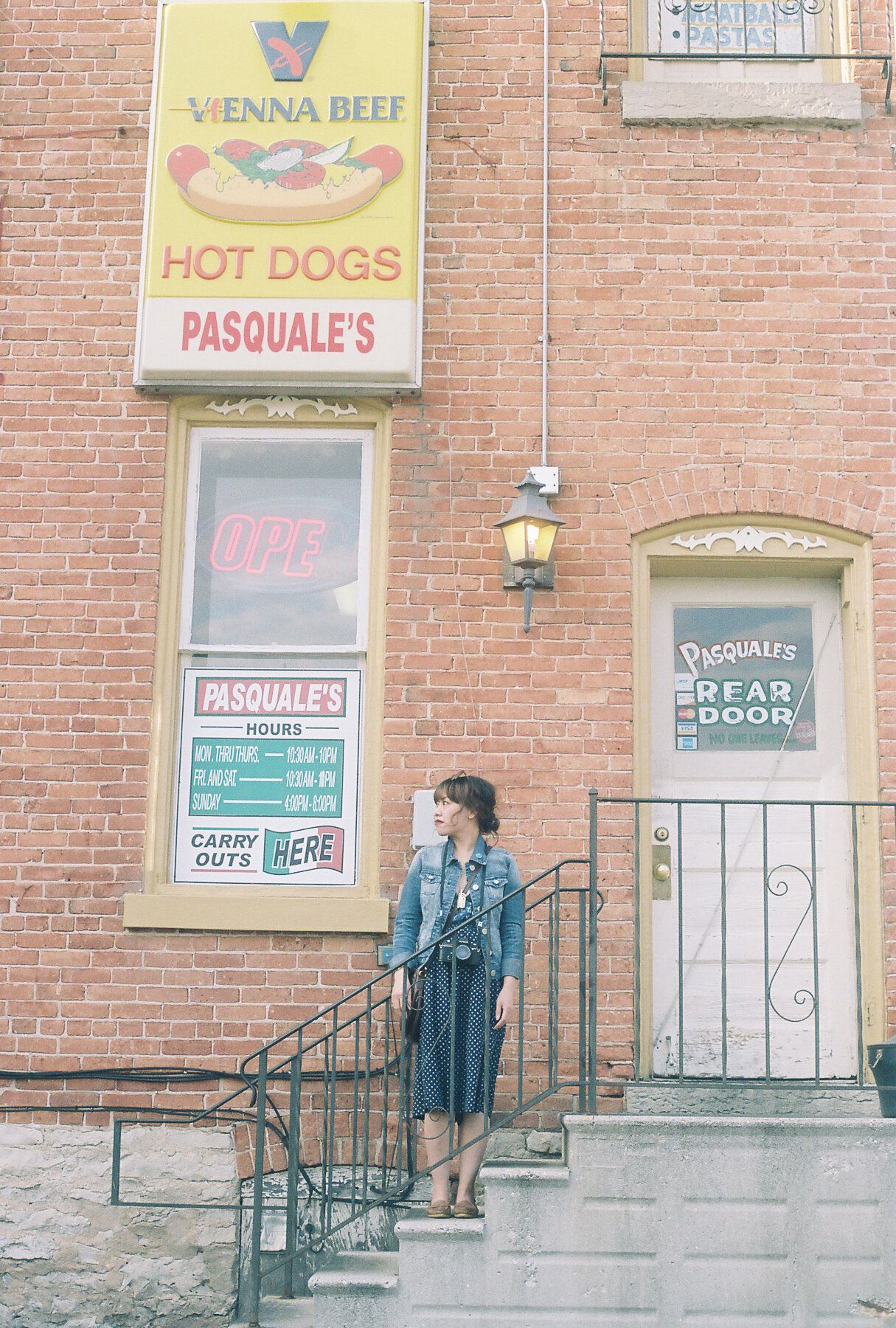 Four sequential photos show a person standing next to a brick building entrance with shop signs and metal railings.