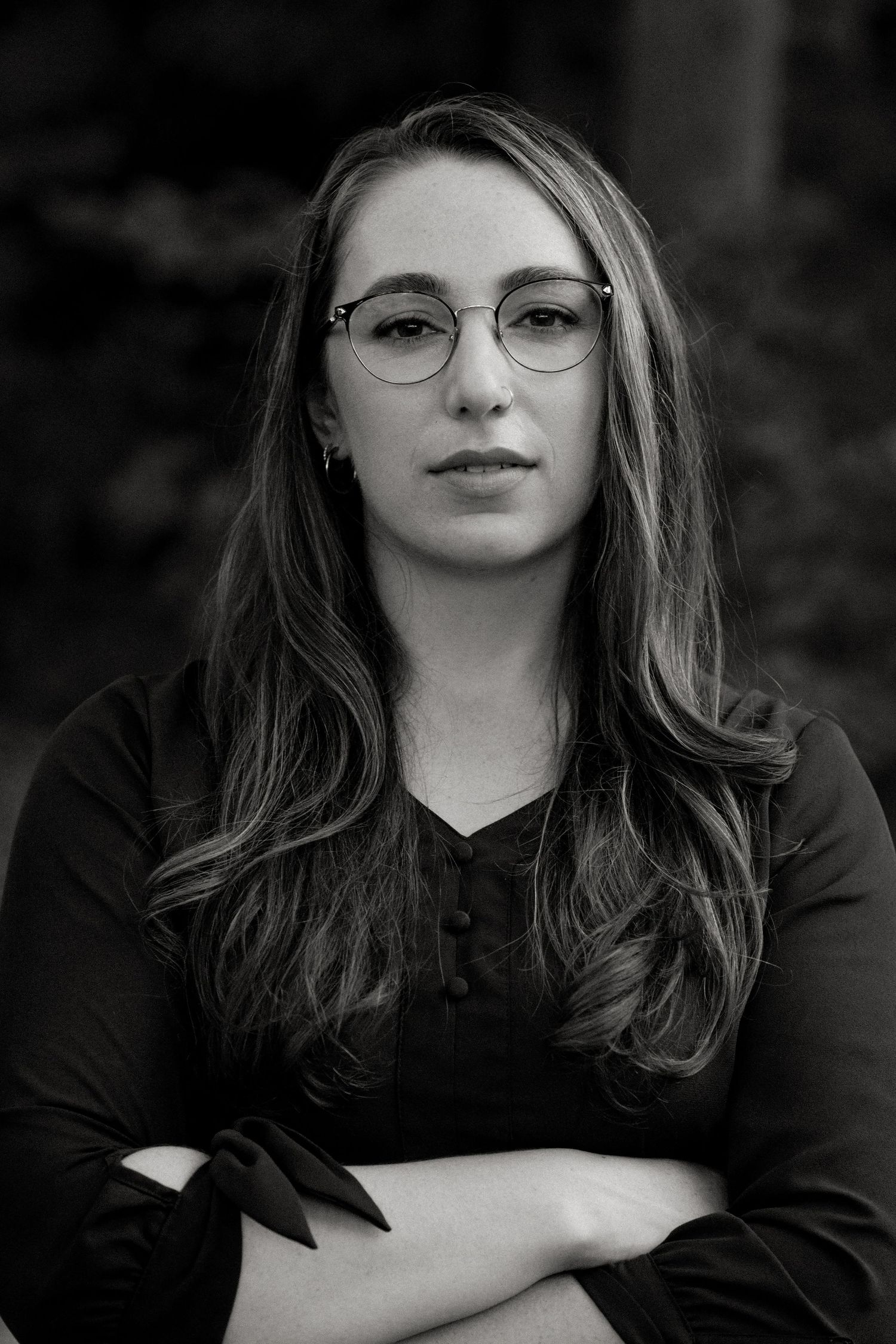 Black and white portrait of a person wearing glasses with a dark background.