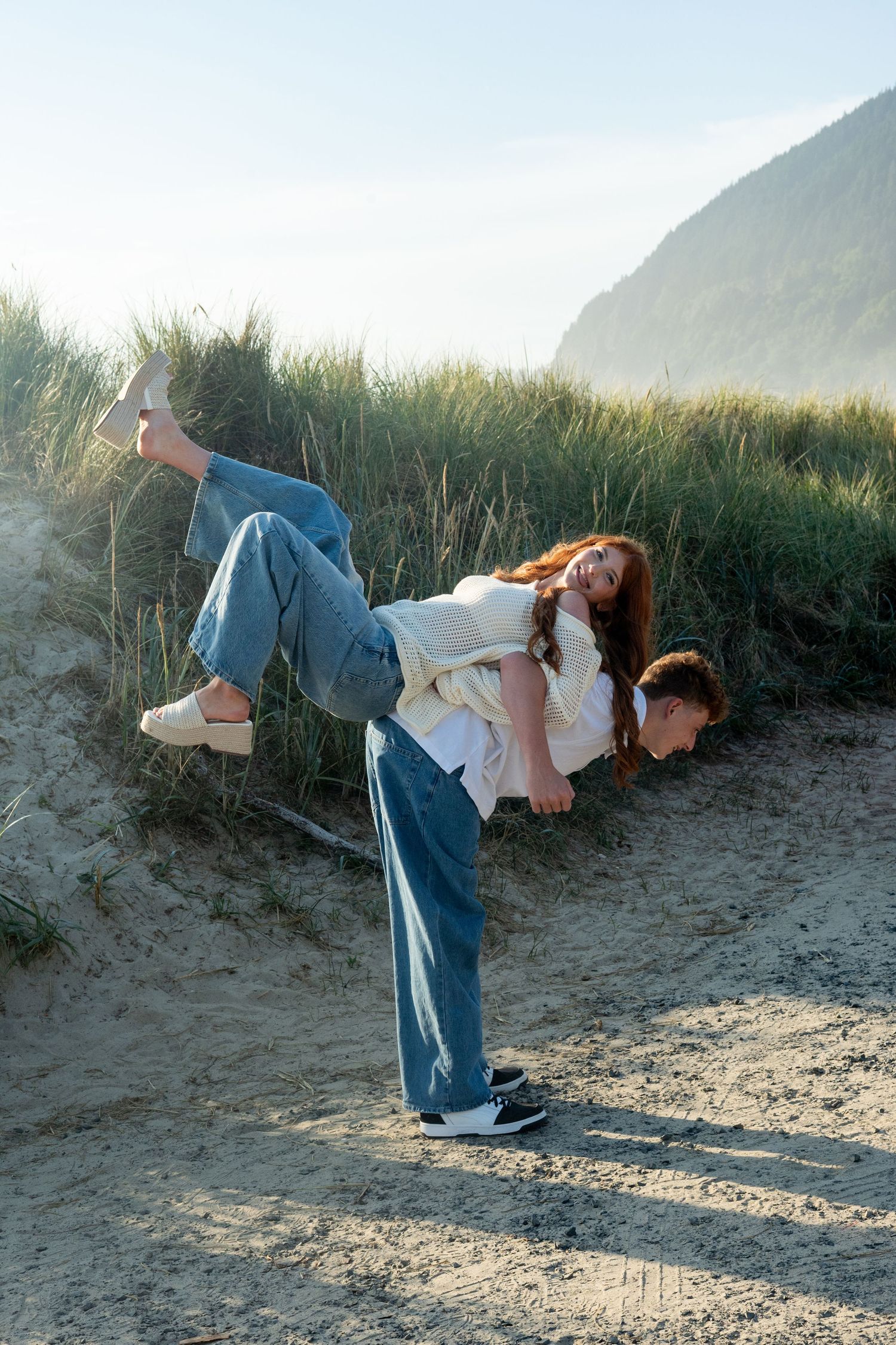 Four sequential photo frames showing a person doing stretching exercises on a sandy beach path at sunset.