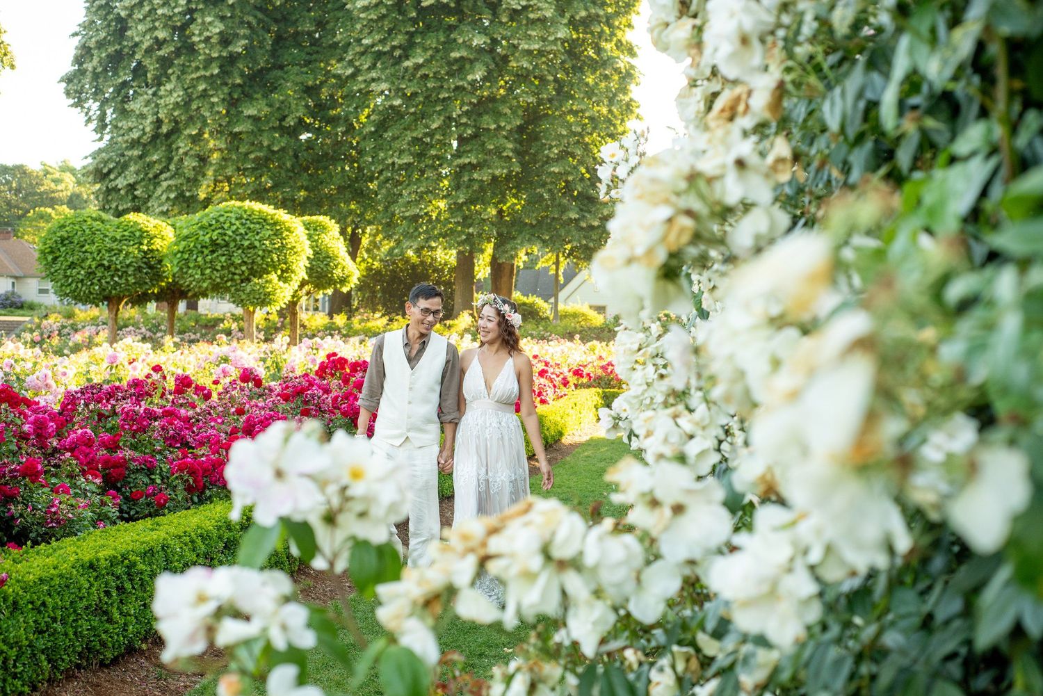 Elegant garden wedding photography with white flowers and manicured hedges in background.