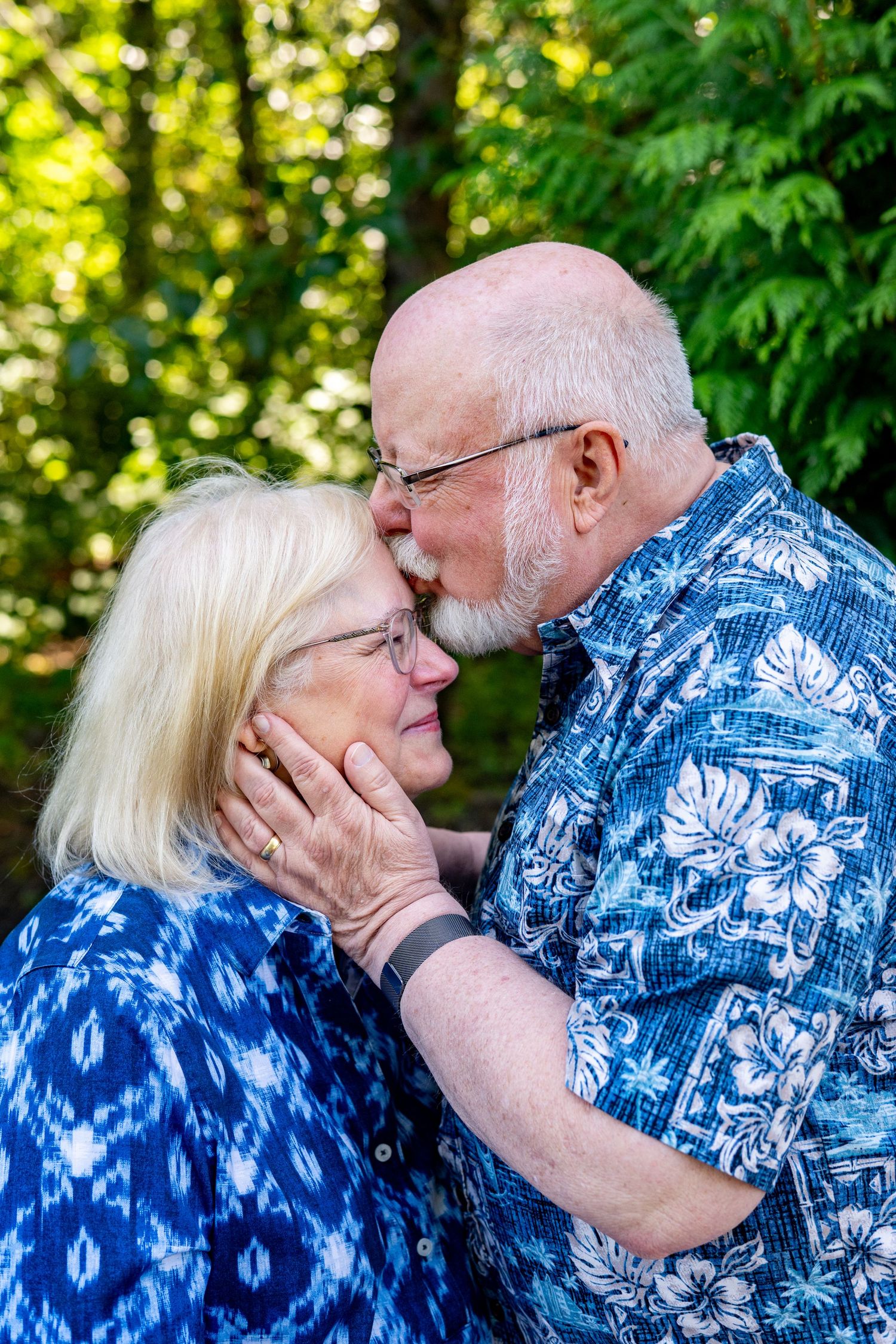 A couple wearing blue and white Hawaiian shirts share tender kisses in a series of photos outdoors.