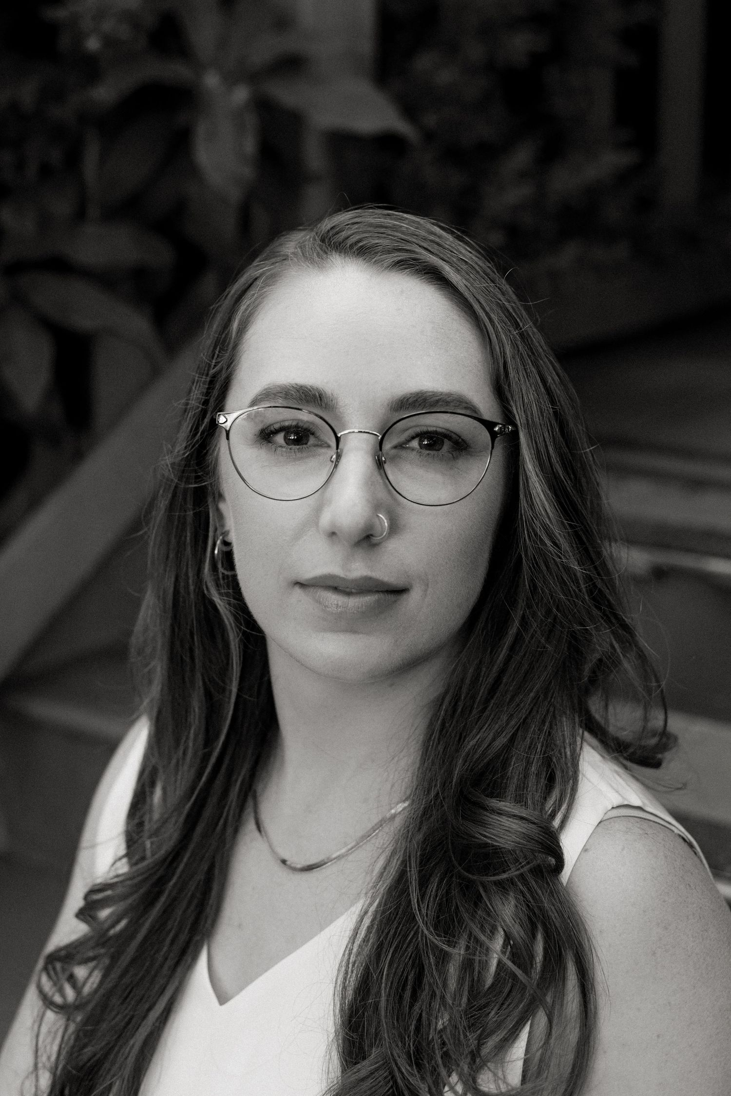 A black and white photo series showing a person with long dark hair and round glasses in different poses.