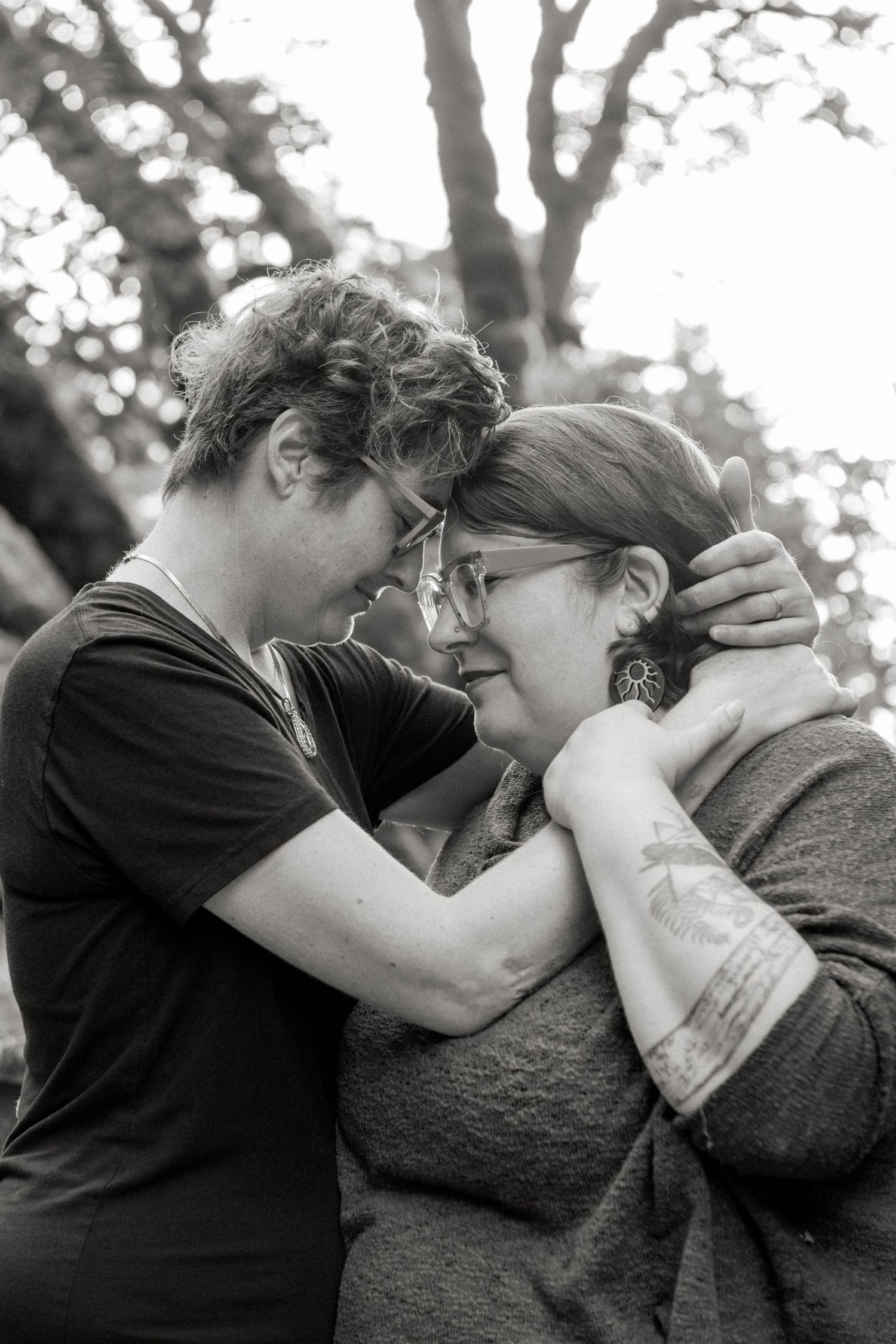 Black and white photo series showing an intimate couple embracing in front of trees.