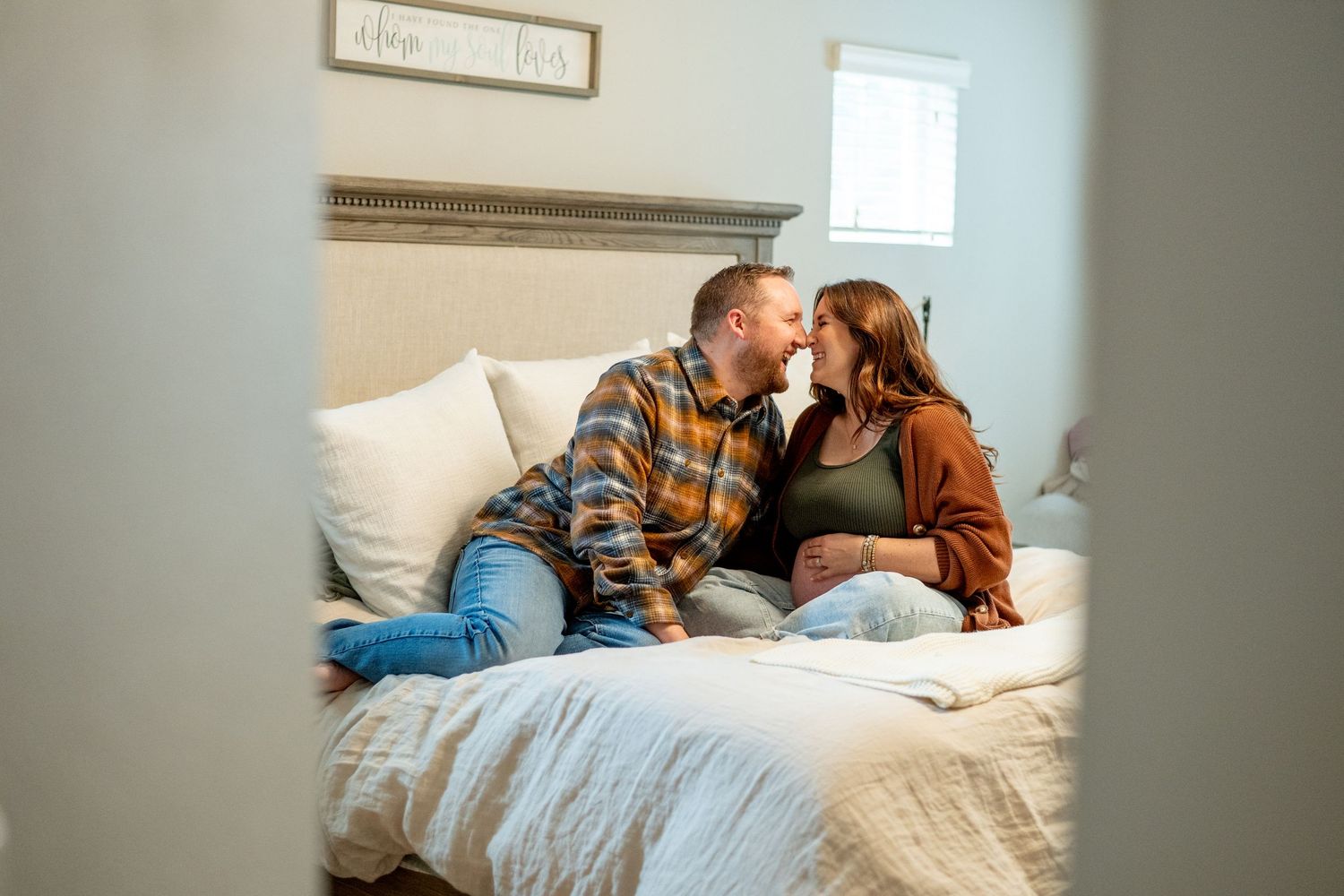 A cozy indoor scene of a couple sharing an intimate moment on a white bed.