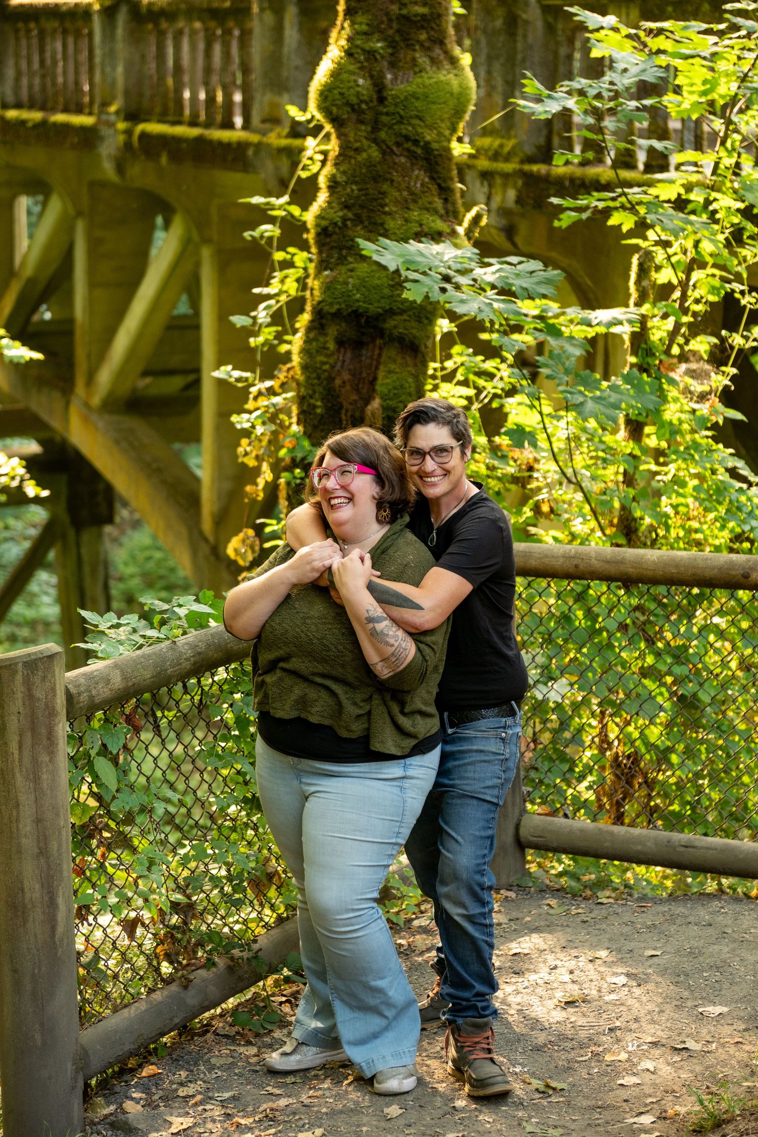 People posing together on a rustic wooden bridge surrounded by lush green foliage in a natural outdoor setting.