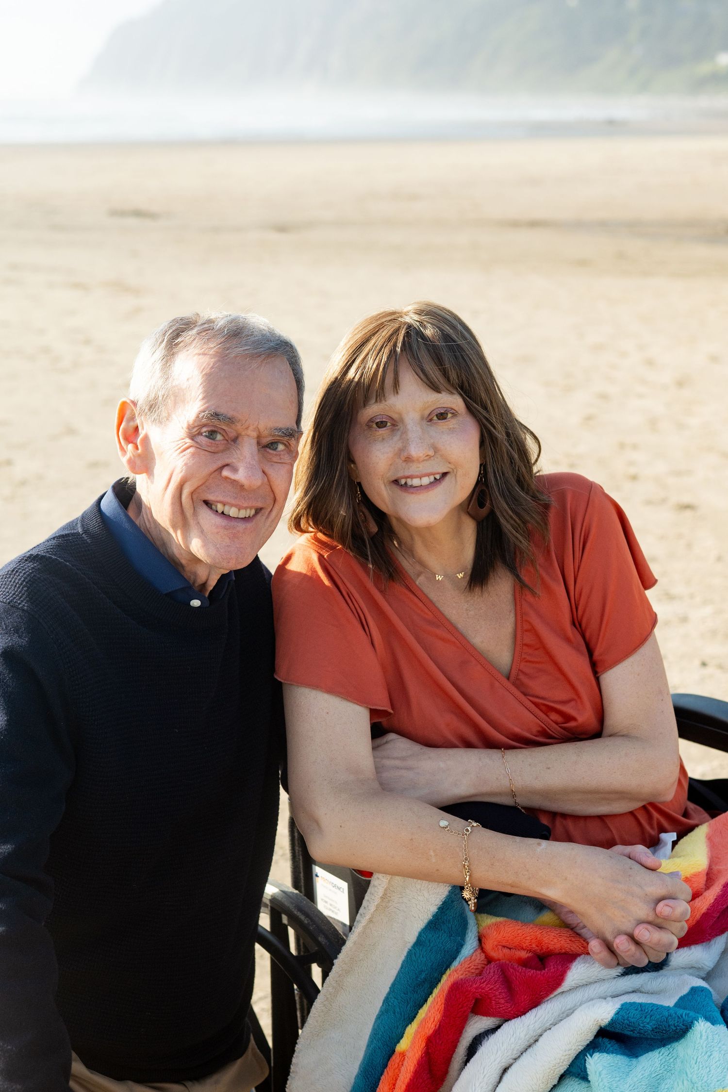A couple relaxes together on a beach while sharing joyful moments at sunset.