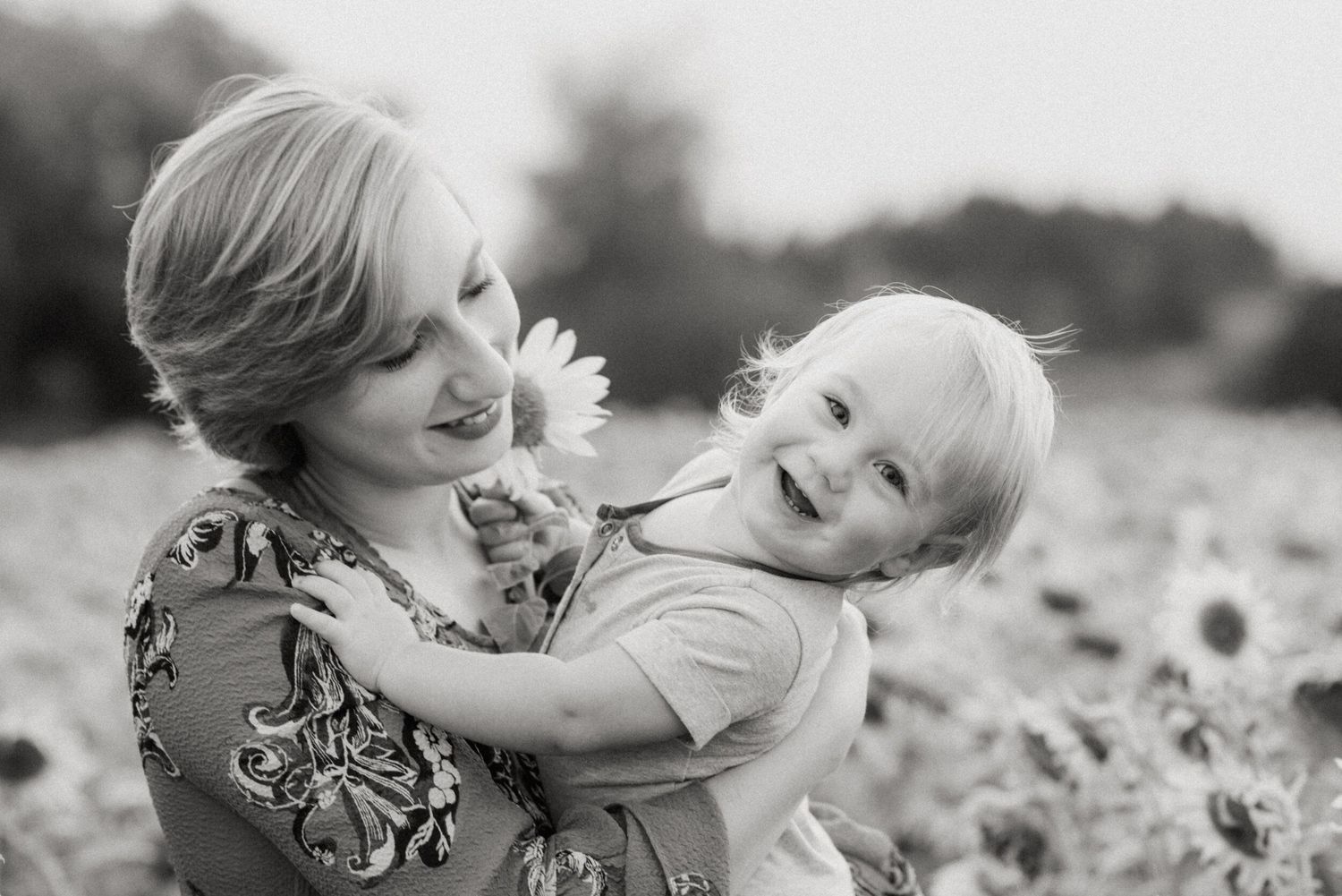 A touching black and white image sequence shows tender moments of affection between a parent and child playing outdoors.