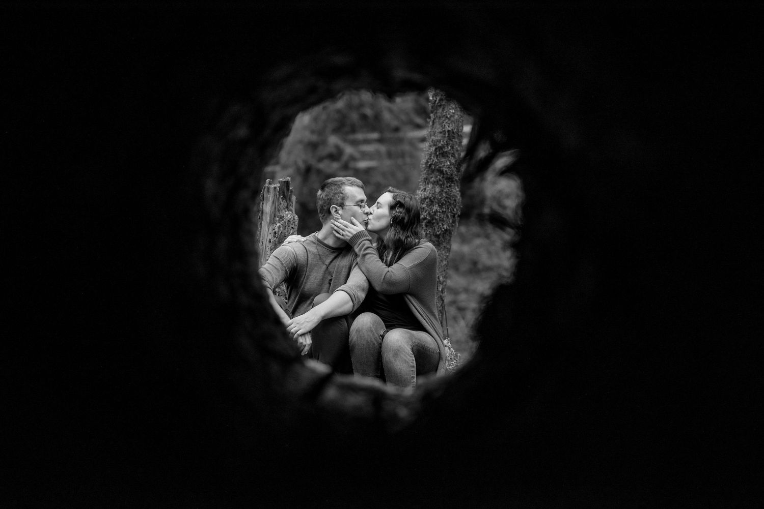 A romantic black and white photo captured through a circular frame showing intimacy.