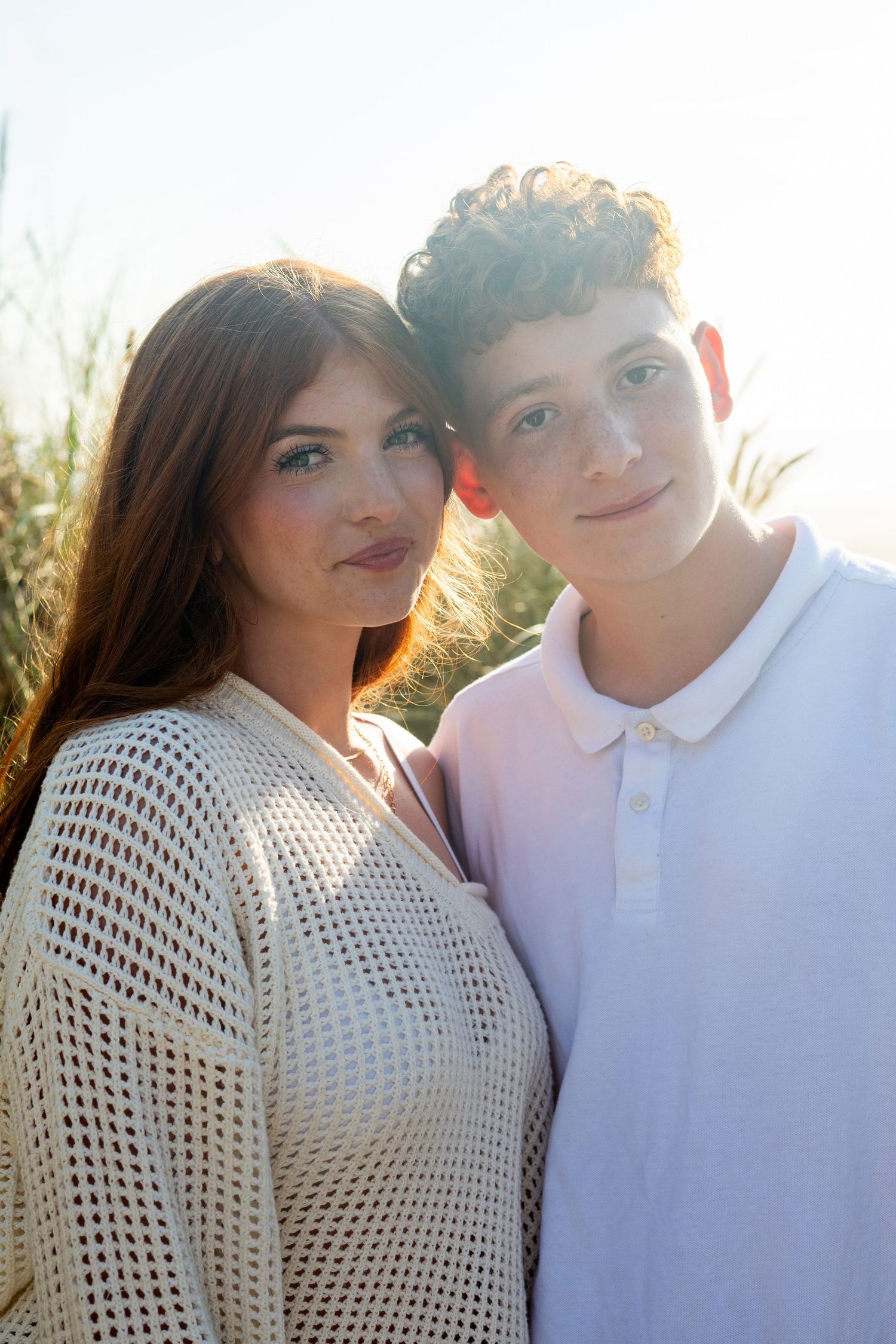 Couple in white outfits pose intimately in series of romantic outdoor golden hour portraits.