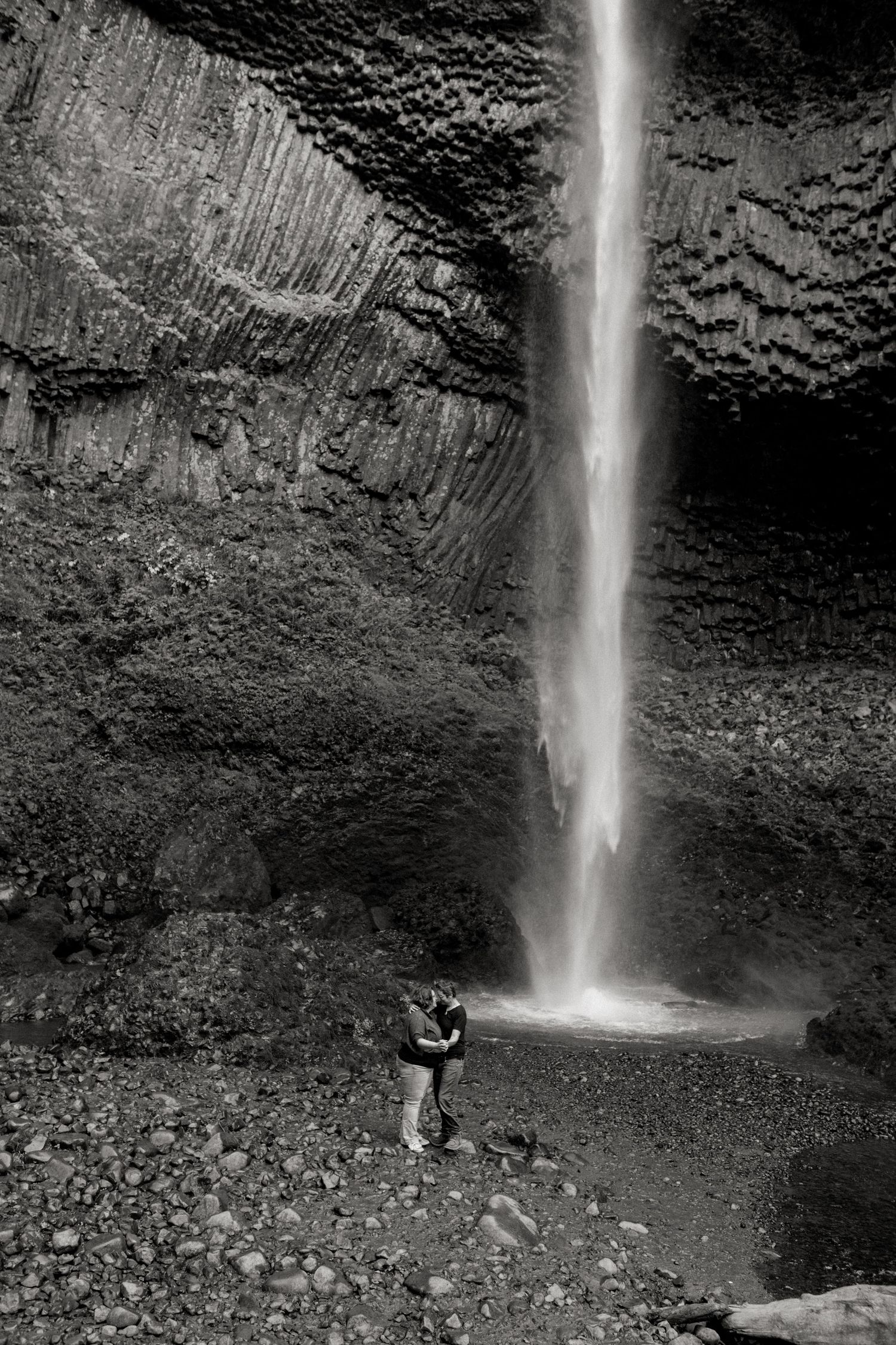 A stunning sequence of Latourell Falls in Oregon cascading down dark basalt cliffs as a figure stands at its misty base.