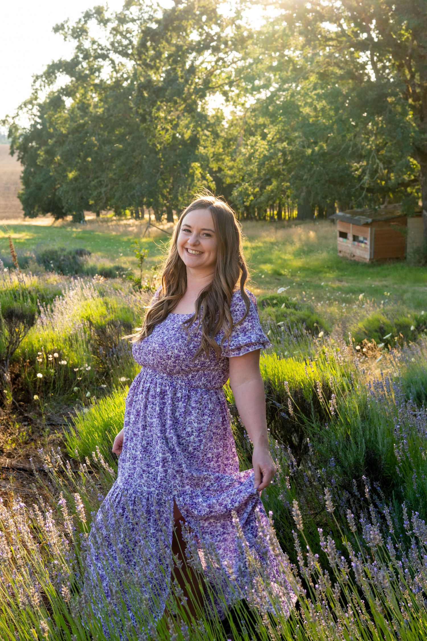 A purple floral dress creates a dreamy summer scene among blooming lavender fields at golden hour.
