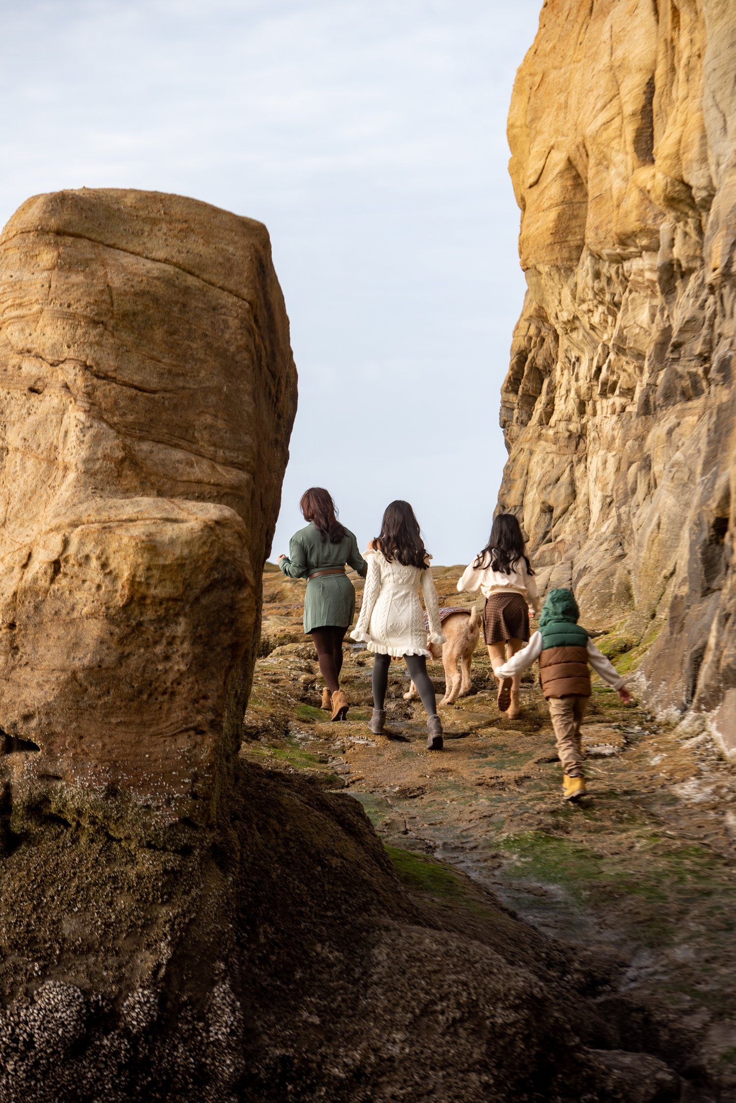 A group hiking up a rocky trail between towering sandstone formations.