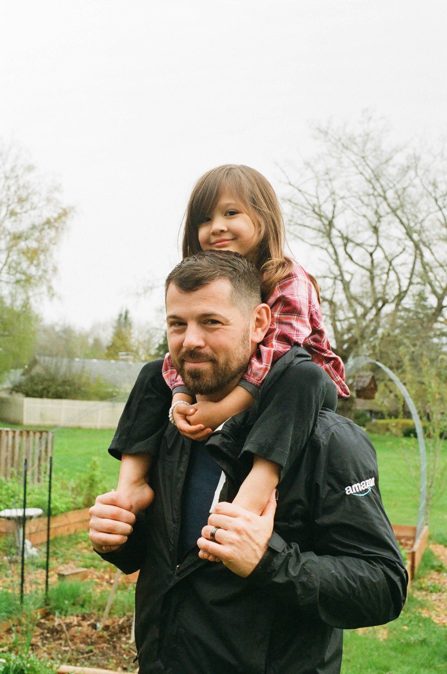 A father and child enjoying quality time in a backyard garden on an overcast spring day.