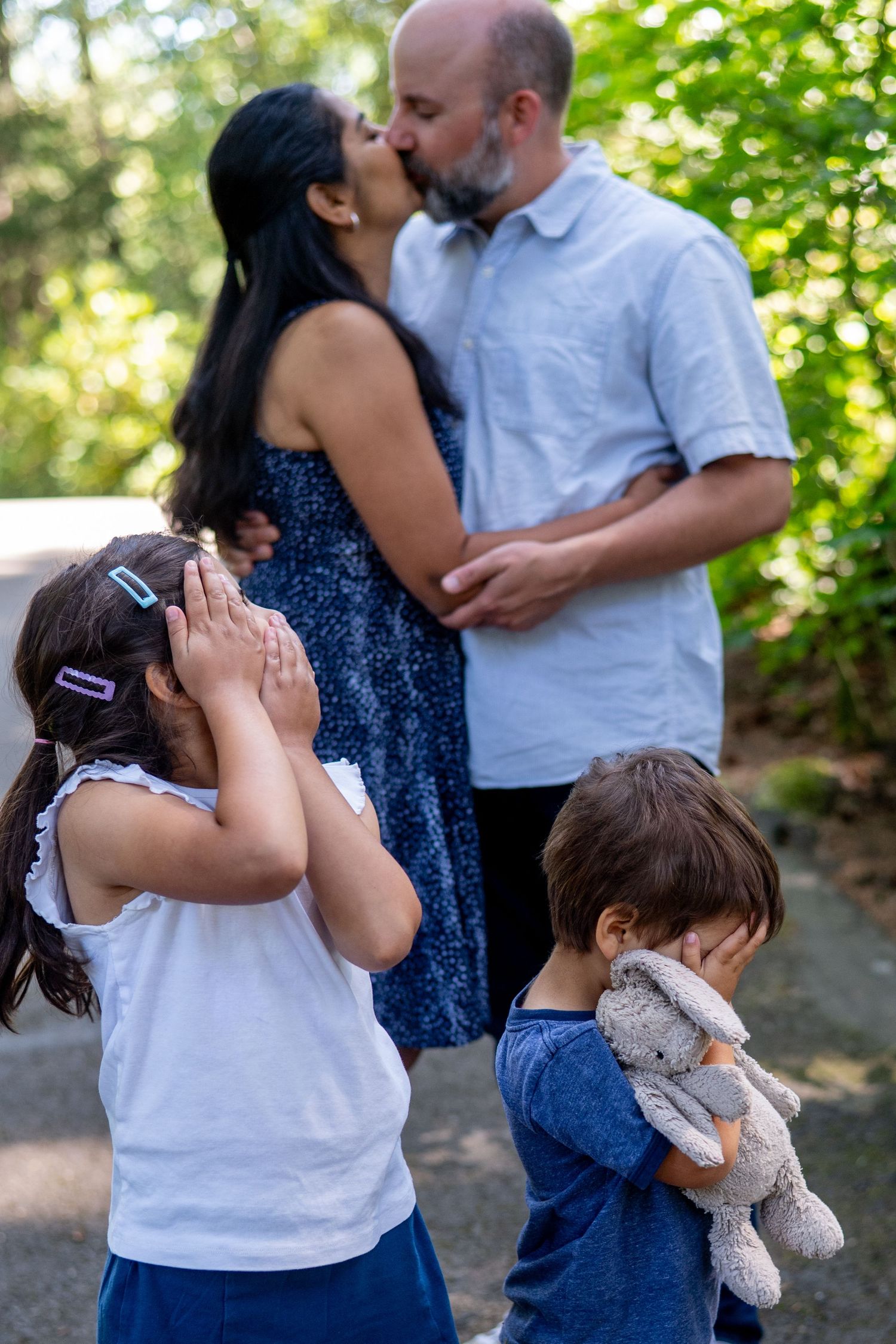 Family embracing together outdoors in a natural setting among green trees and foliage.