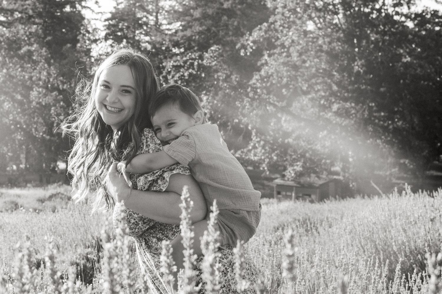Two people playing joyfully in a sunlit meadow with tall grass on a bright summer day.