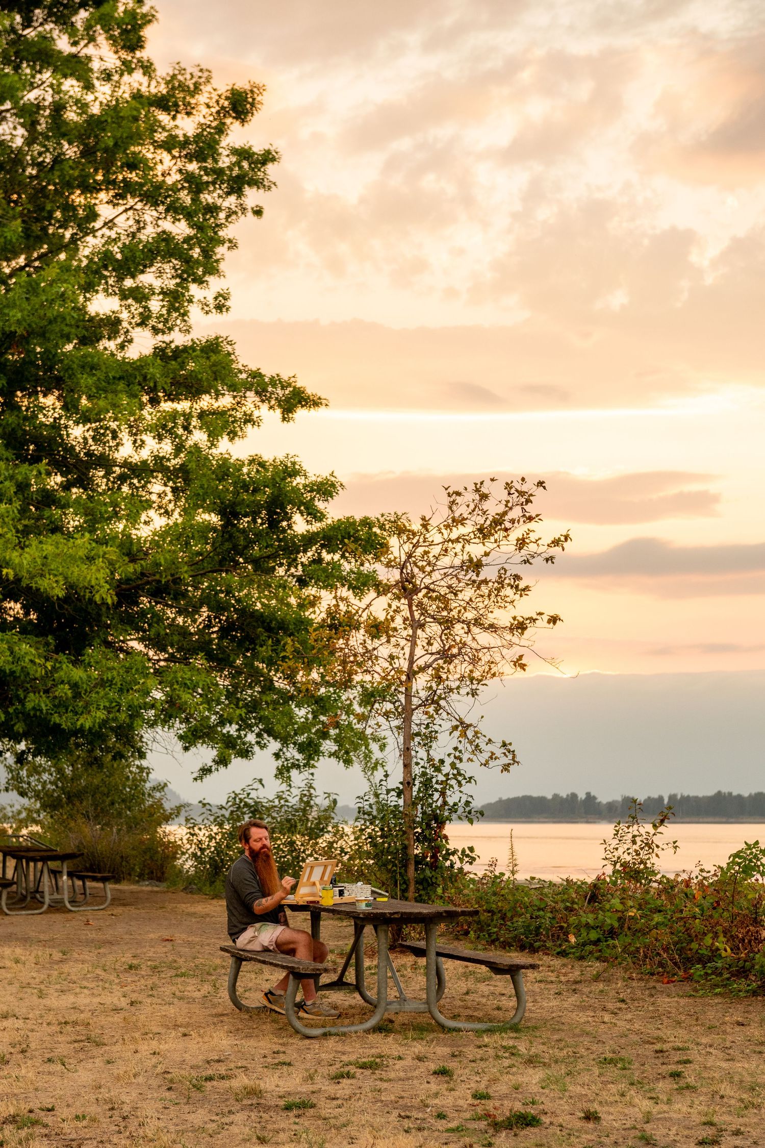People enjoying a relaxing evening at a scenic lakeside picnic area during golden hour sunset.