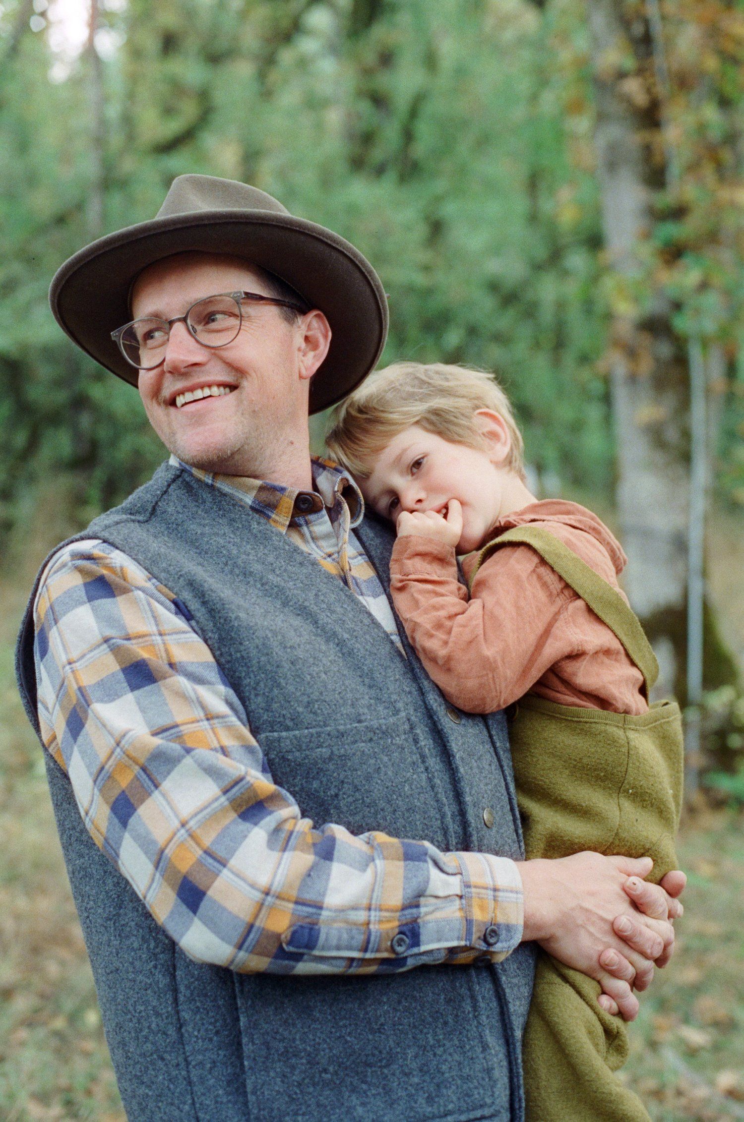 A tender moment captured outdoors showing affection between two figures in autumn clothing.