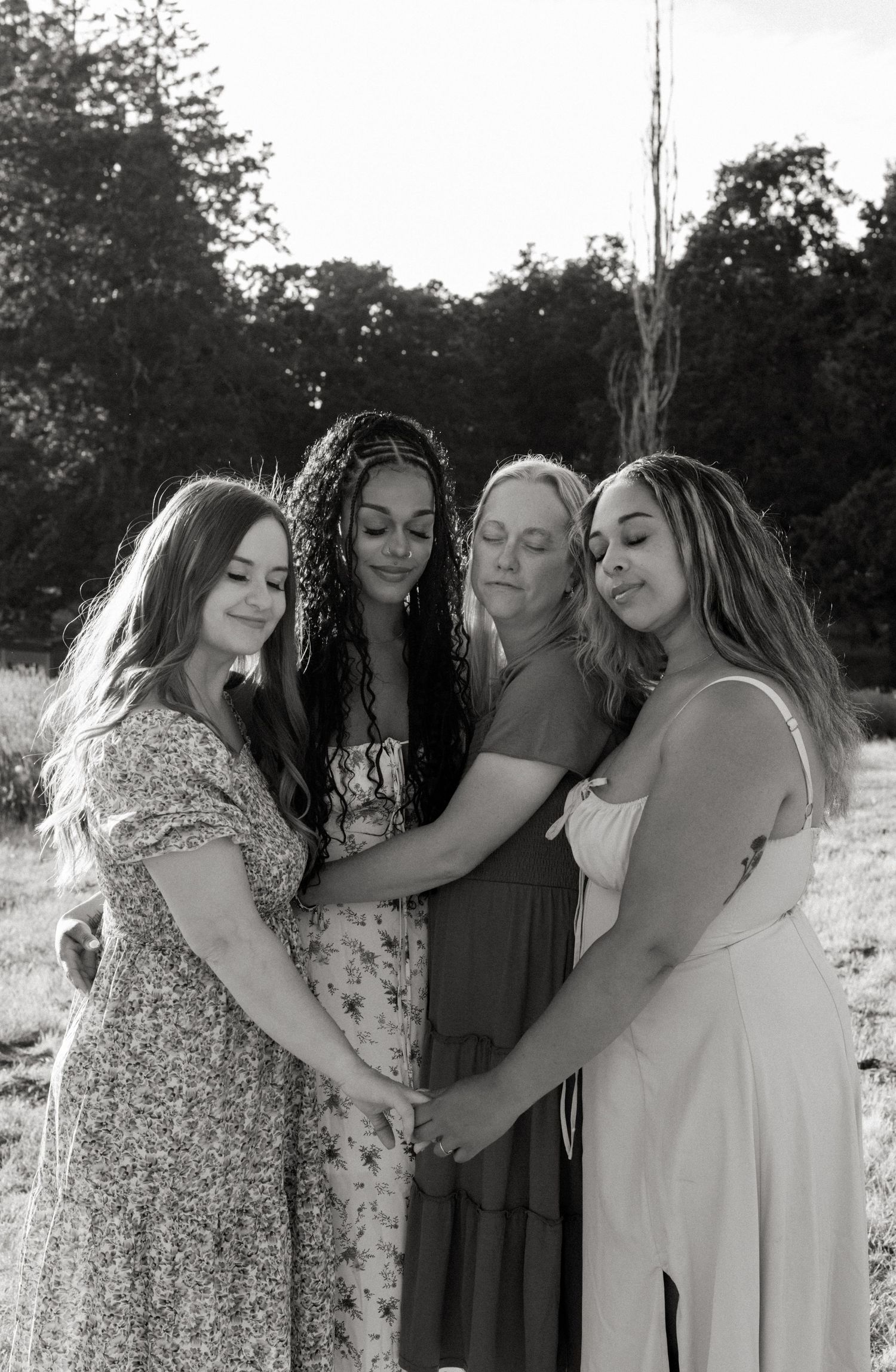 Black and white photo series showing a group in coordinated dresses posing playfully together outdoors.