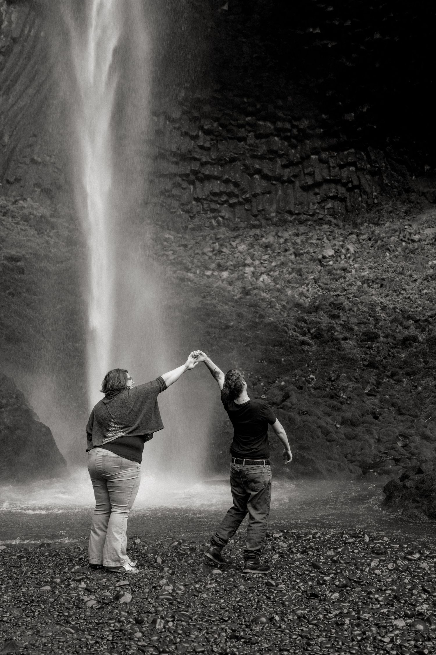 Three black and white sequential photos show people playing and posing near a dramatic waterfall cascading down cliffs.