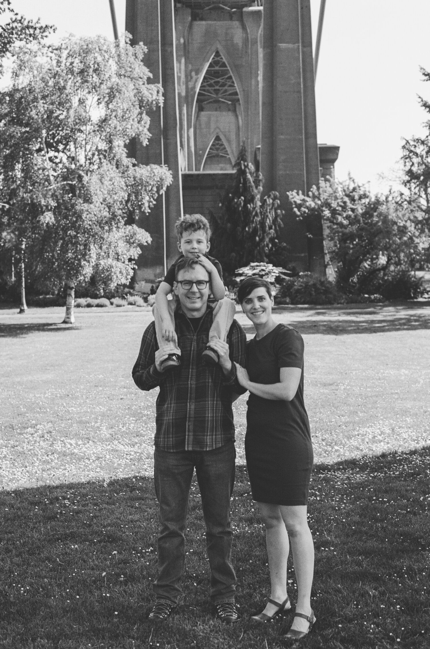 Two people stand and play together on a grassy lawn outside a Gothic-style church or cathedral in black and white.