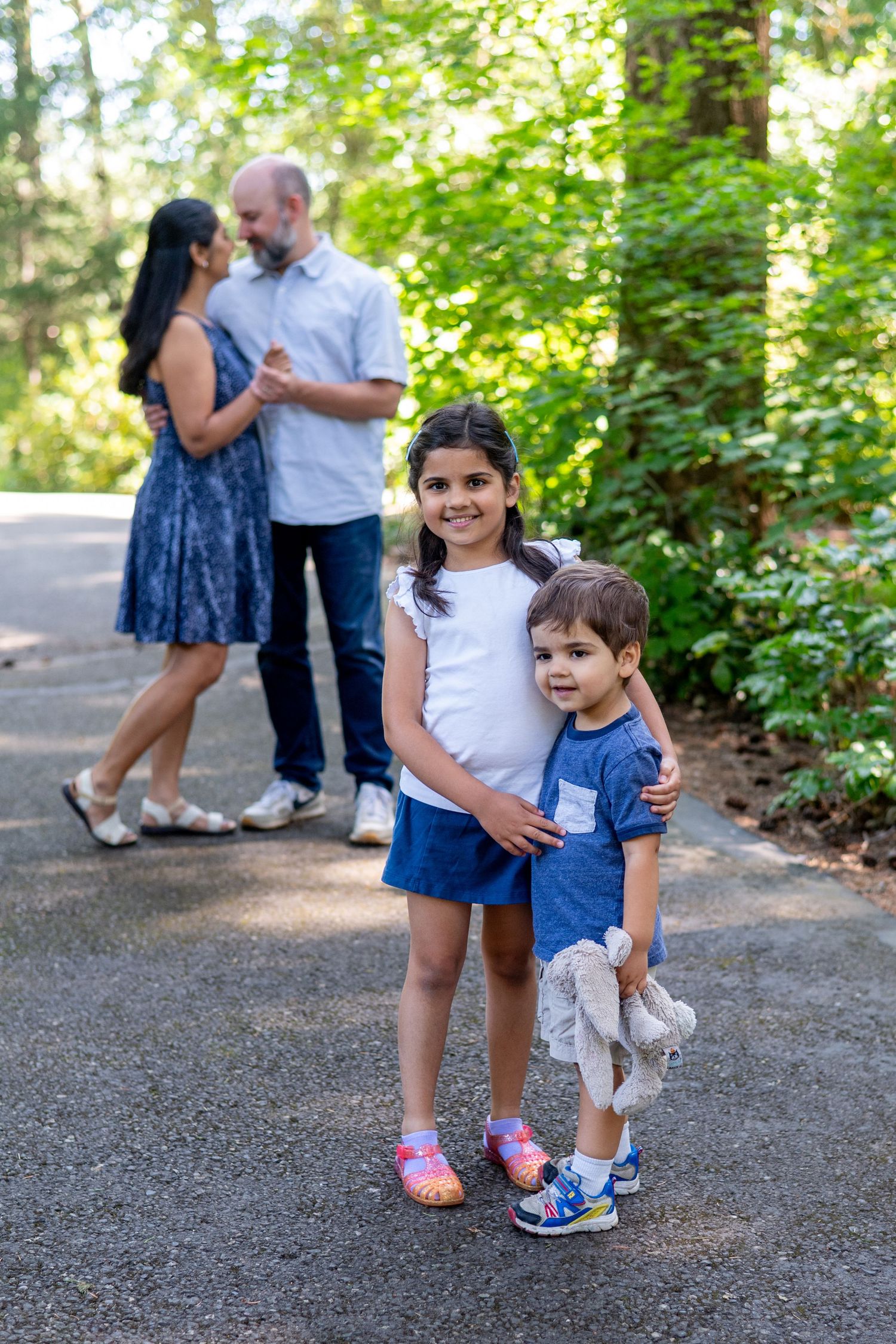 Family enjoys a playful moment on a tree-lined path during an outdoor portrait session.