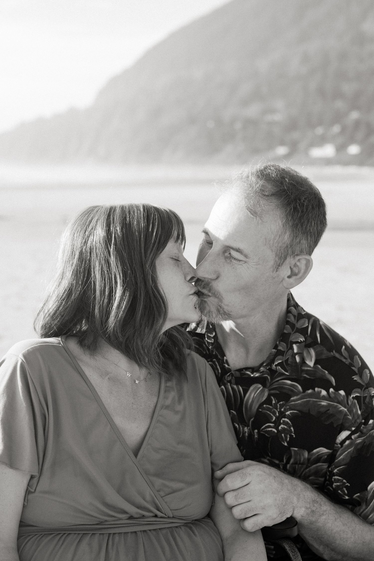A romantic black and white photo series of a couple sharing tender moments by the water.