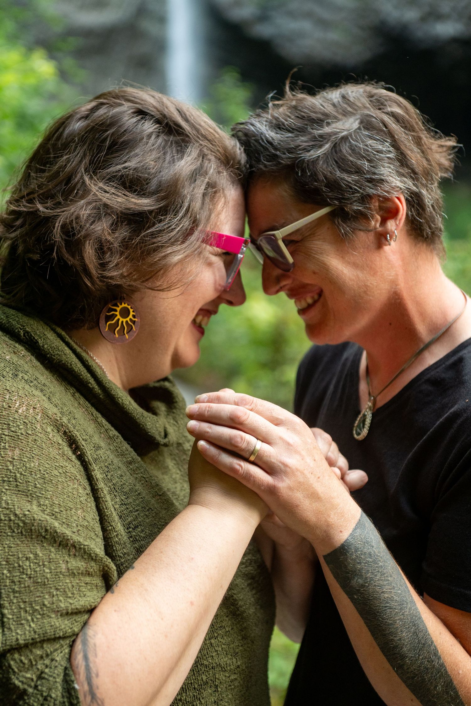 Two people in close embrace share an intimate moment outdoors with one wearing a green sweater.