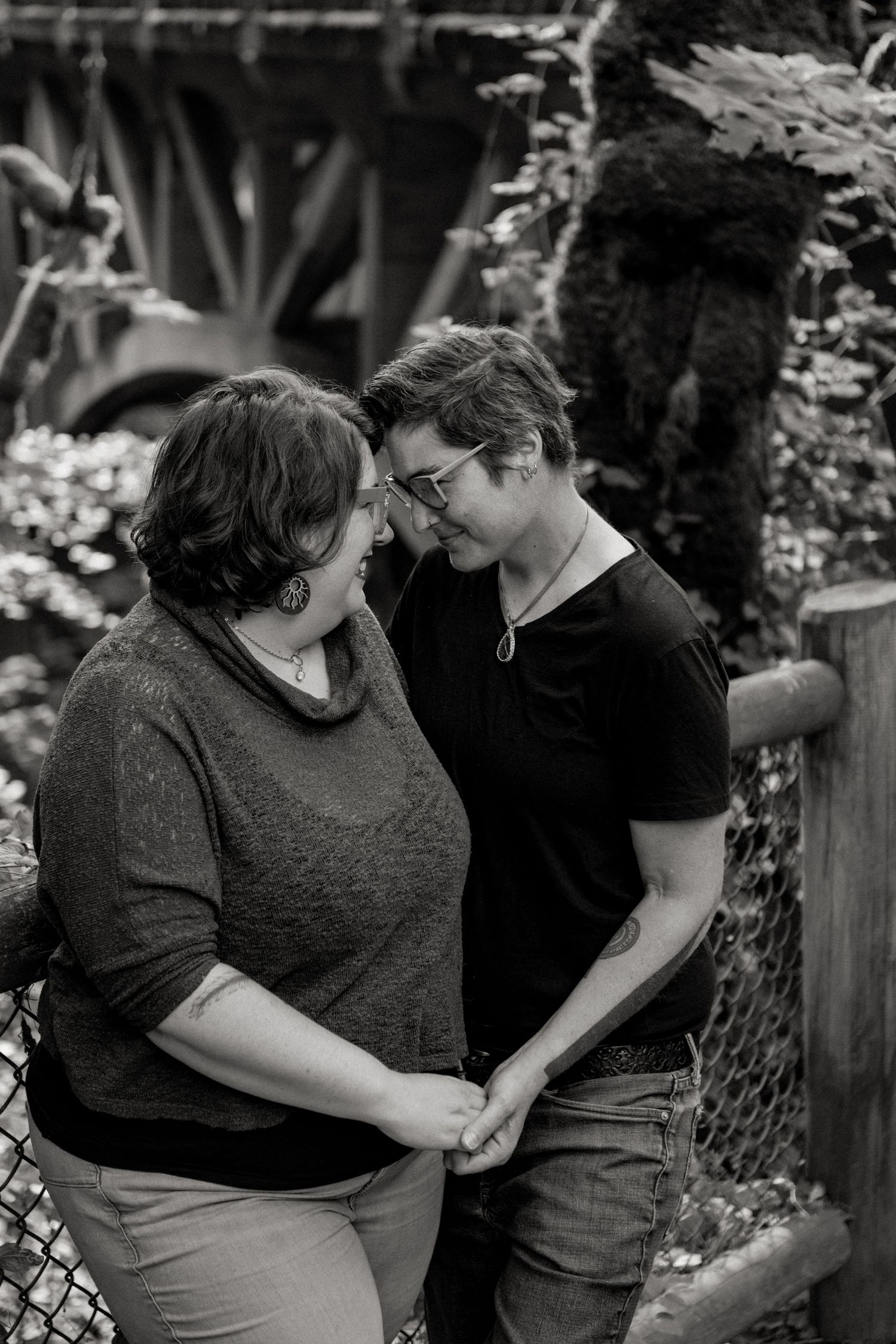A romantic black and white photo of a couple holding hands and sharing an intimate moment in a garden setting.