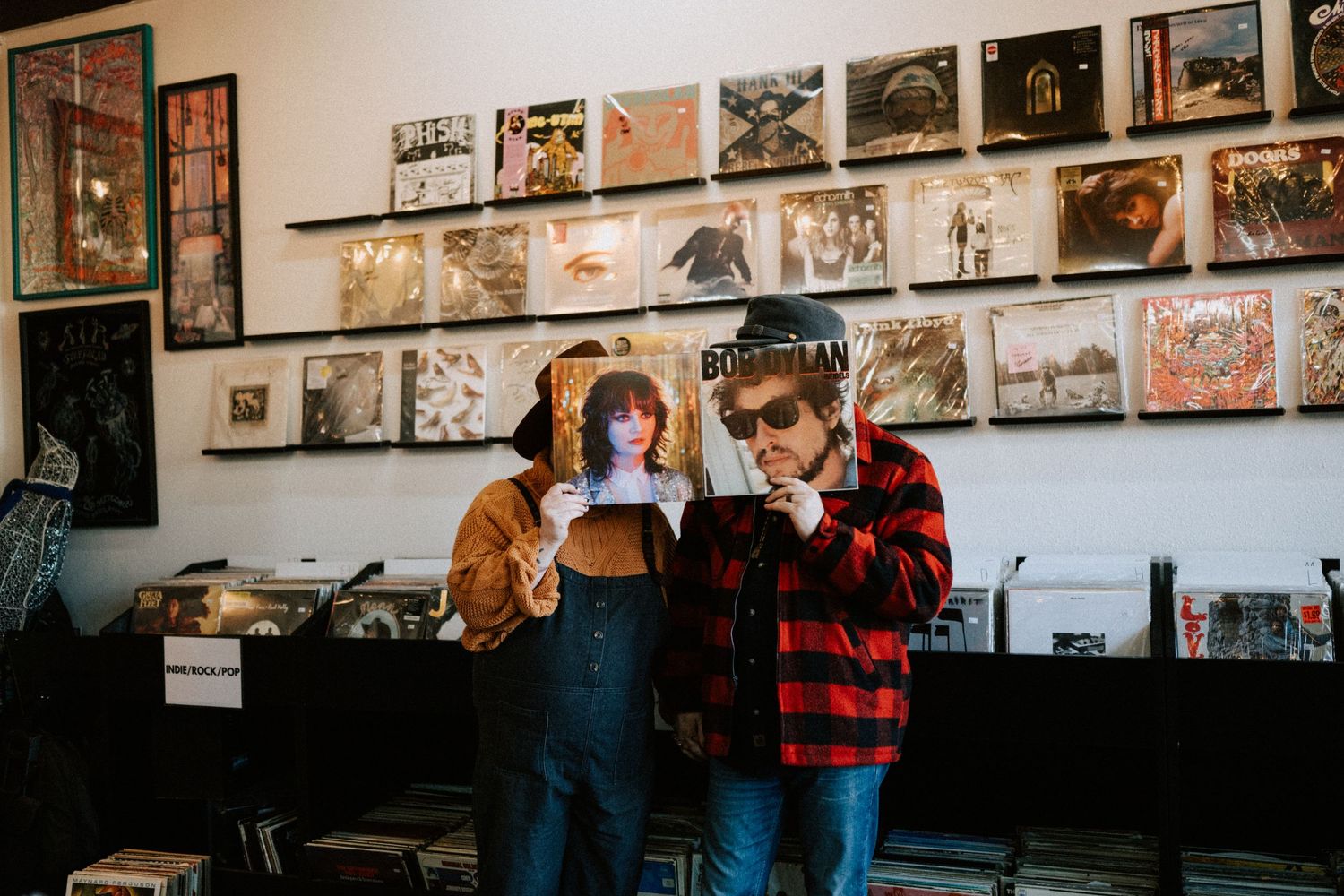 People browsing inside a record store with album covers displayed on the walls.