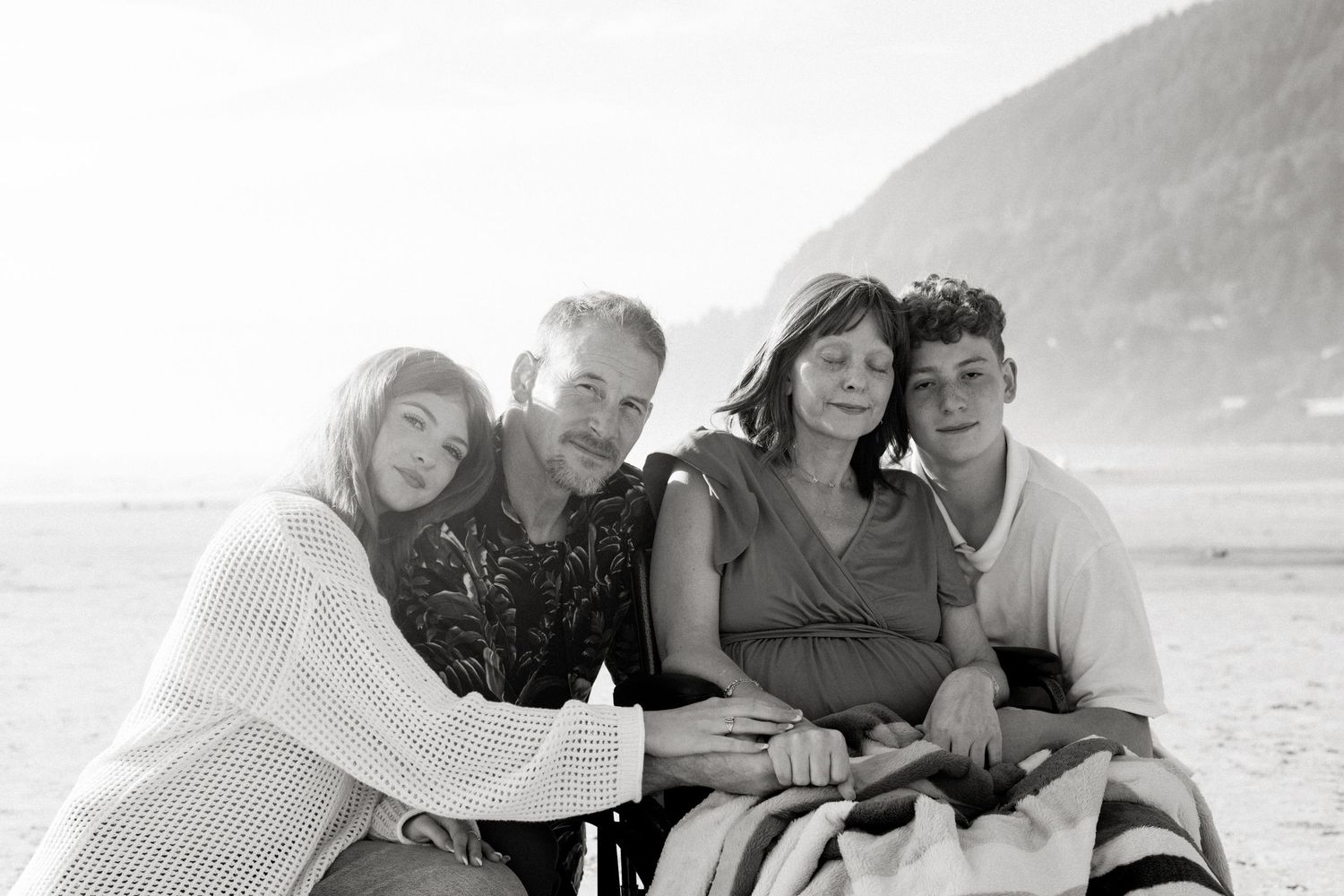 Group of friends laughing and embracing while enjoying time together at a scenic outdoor beach location.