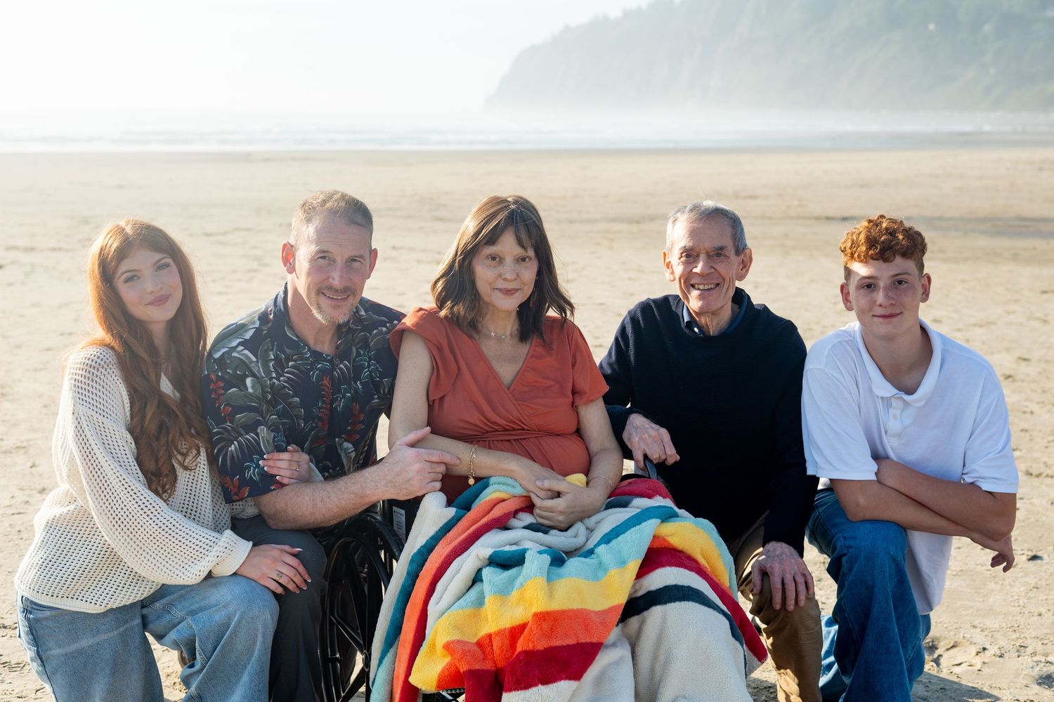 Happy family enjoying quality time together while sitting on a sandy beach at sunset.