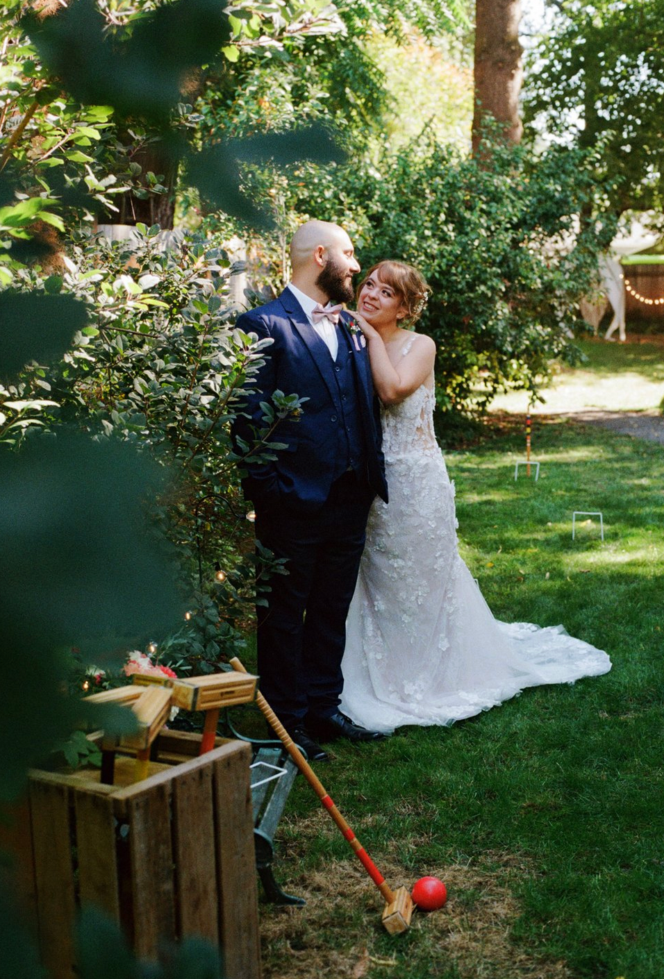 A wedding couple shares a tender moment in a garden setting with rustic wooden decor.