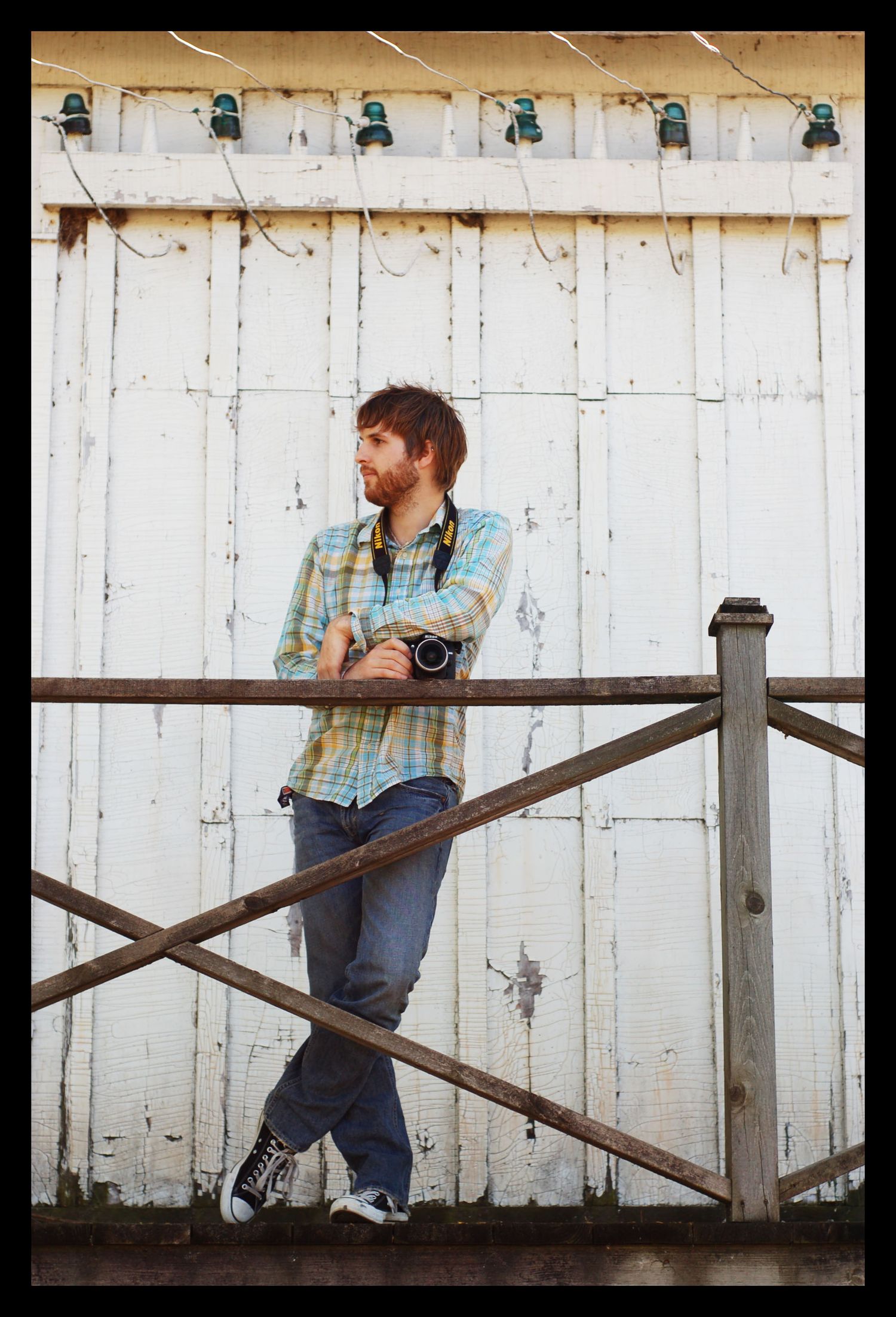 Subject sits casually on a rustic wooden fence against a weathered white wall in a series of four contemplative poses.