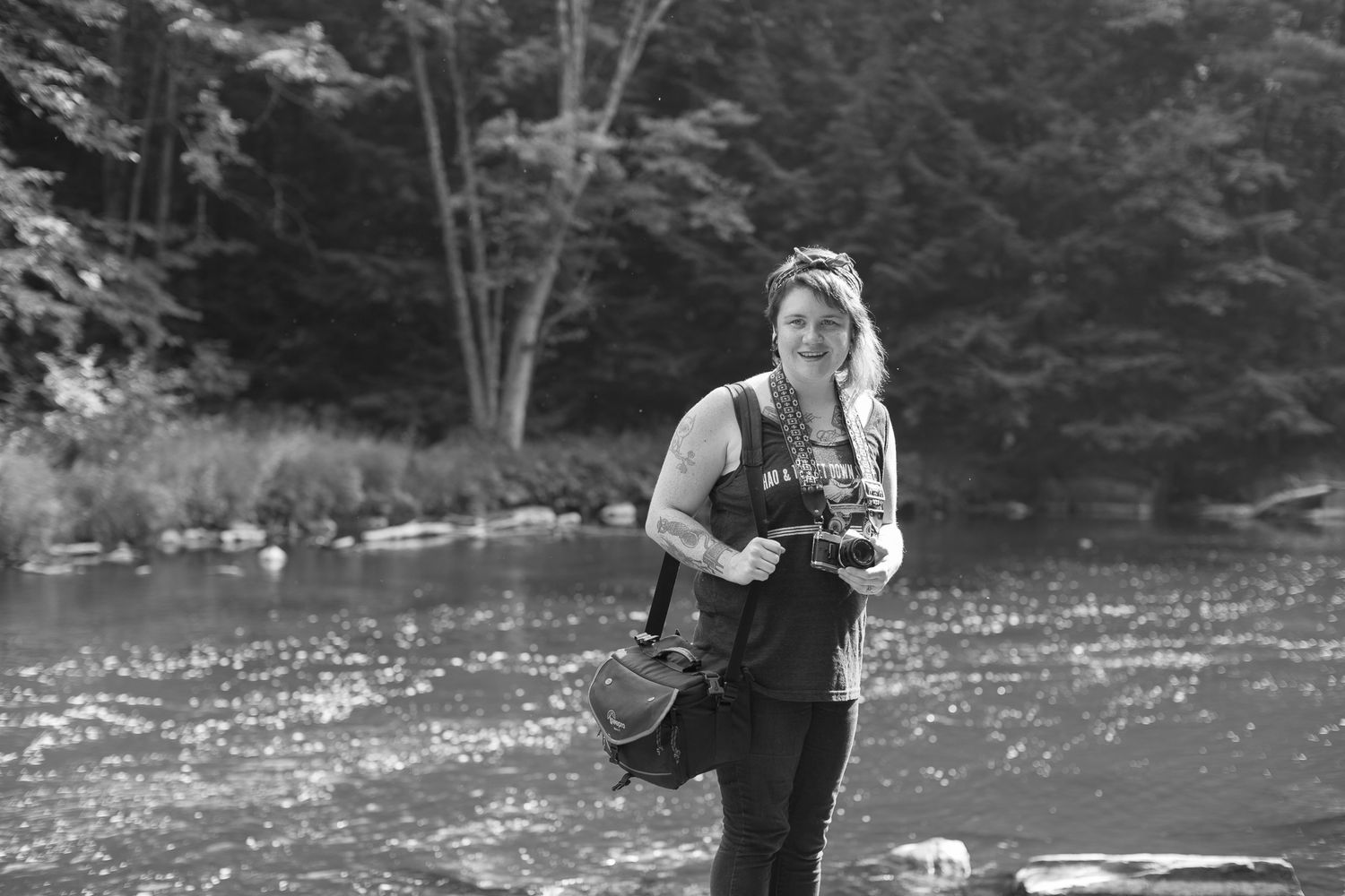 A person fly fishing in a serene river surrounded by lush forest on a calm day.