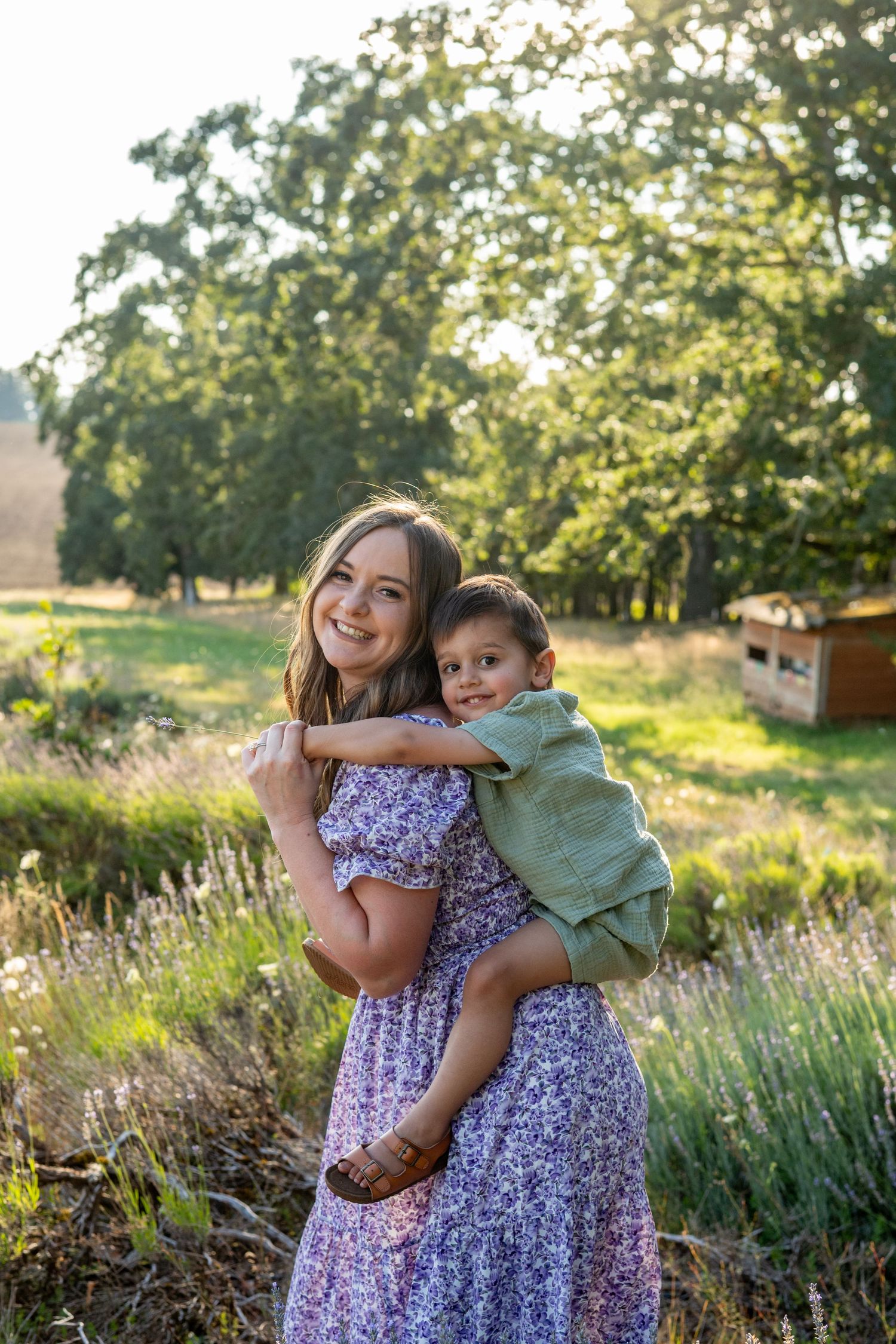 A joyful moment captured in a sunny garden with a floral dress and green shirt against trees and lavender plants.