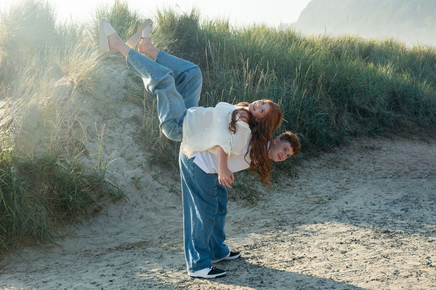 Two people having fun on a dusty dirt path in nature with sunlit backlighting during golden hour.