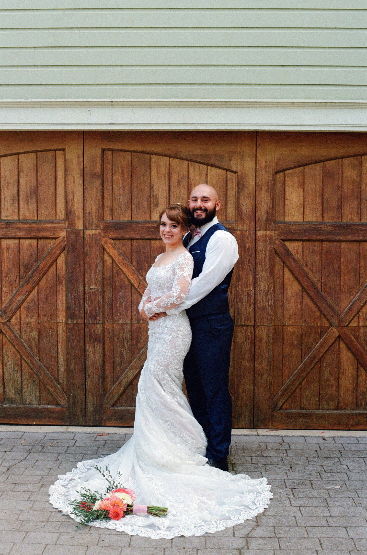 A series of romantic wedding photos showing a bride in lace dress and groom embracing against a rustic wooden barn door backdrop.