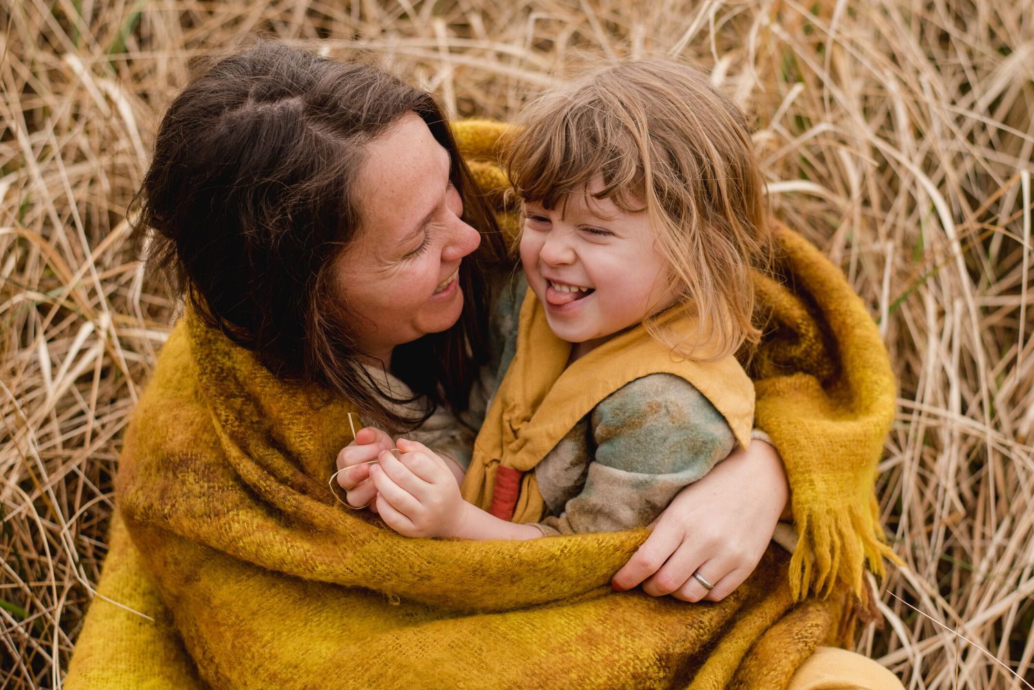 A candid moment of joy and laughter between two people in a golden wheat field at sunset.
