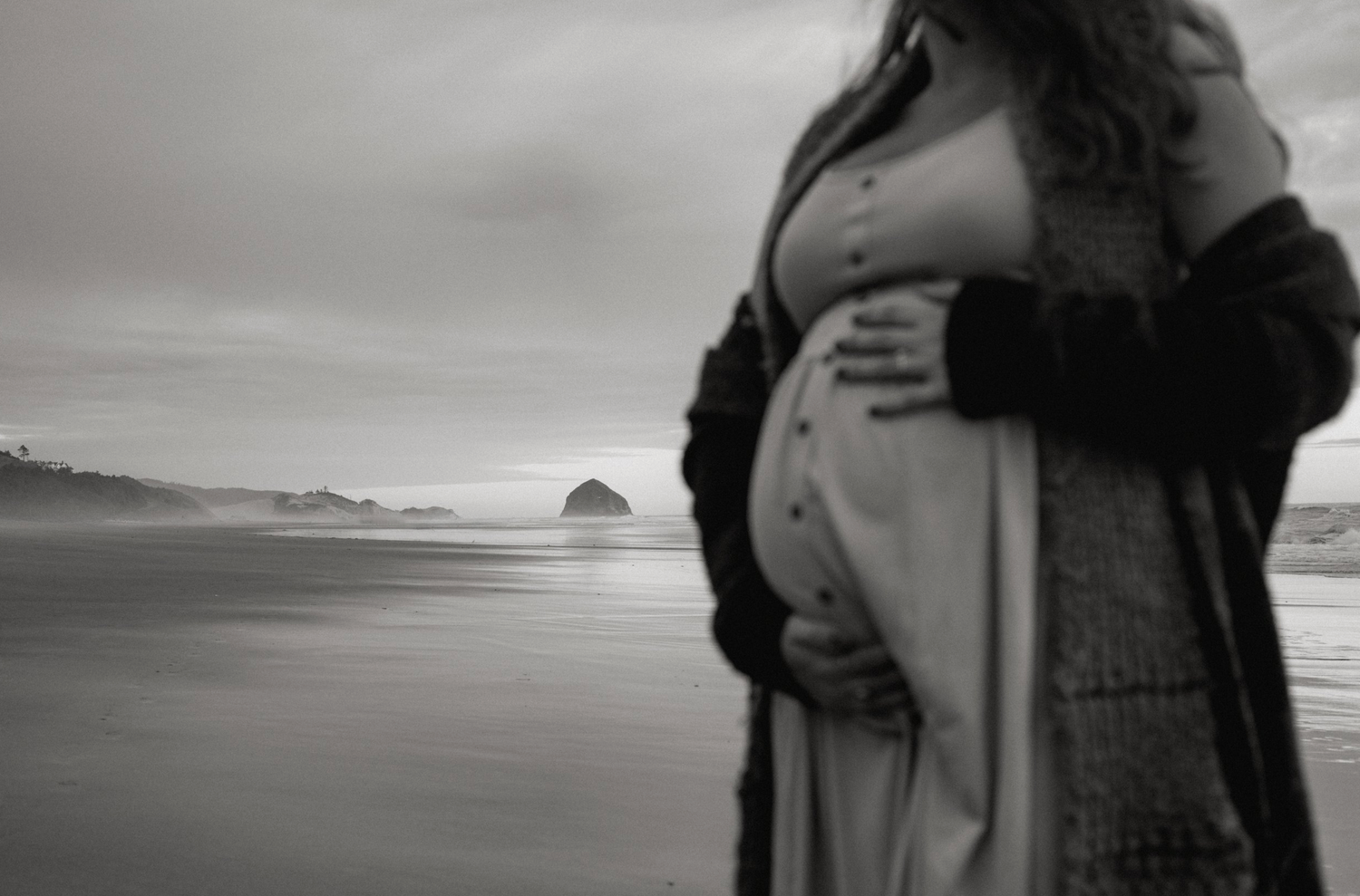 Atmospheric black and white seaside embrace captured against moody sky.
