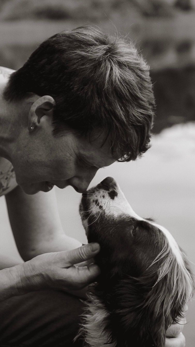 A person shares a tender nose-to-nose moment with a Cavalier King Charles Spaniel in black and white.