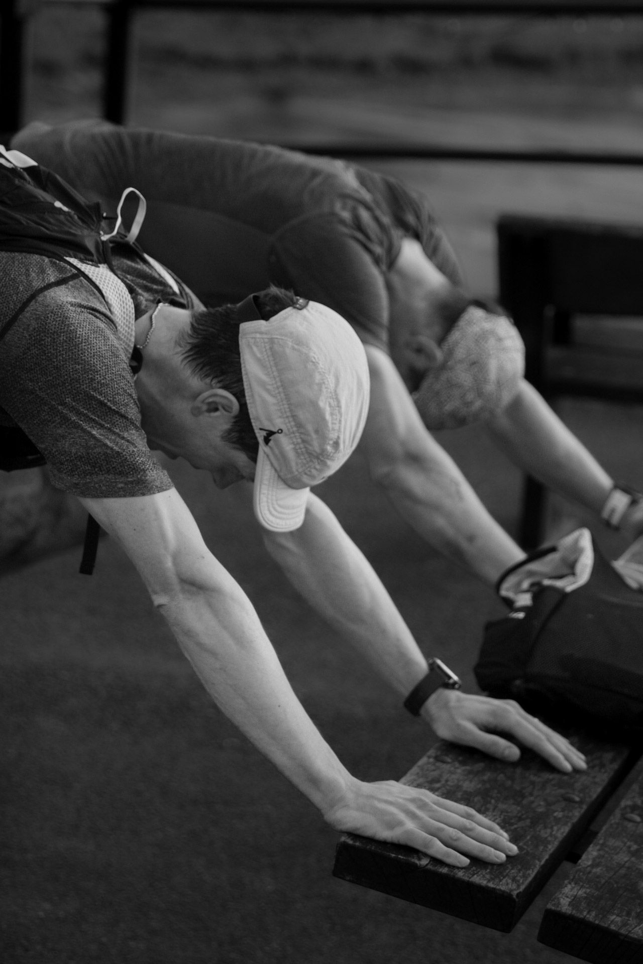 Black and white photo of athletes performing stretching exercises on blocks during an indoor training session.