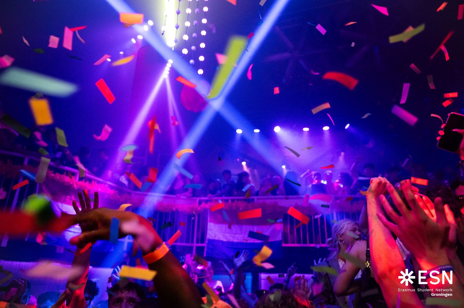 Colorful confetti raining over excited crowd at ESN club event with vibrant blue and purple lights.