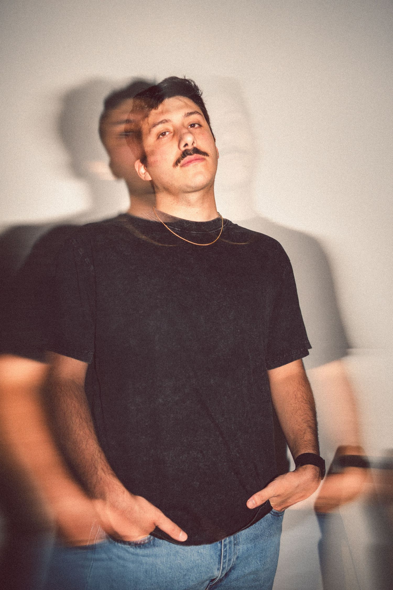 Young man with mustache in black t-shirt and jeans posing with a motion blur double exposure effect.