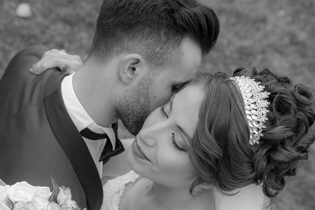 Black and white wedding photo of bride and groom sharing a romantic moment, bride wearing a pearl tiara.
