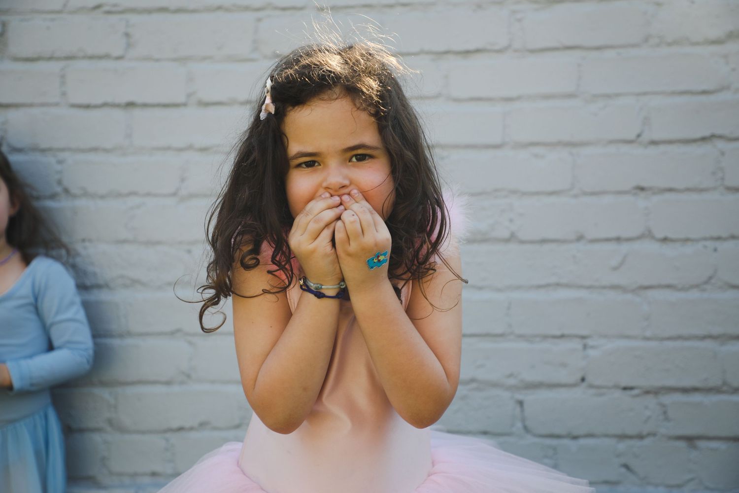 Girl in tutu making shy expression against brick wall, Sydney family photography