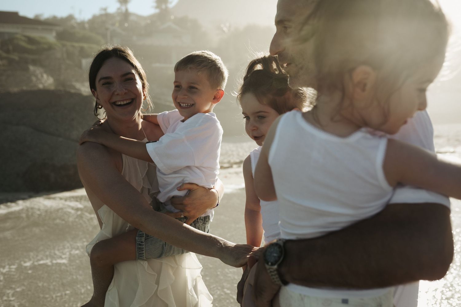 Mother laughing with children gathered around on the beach, Sydney family photographer